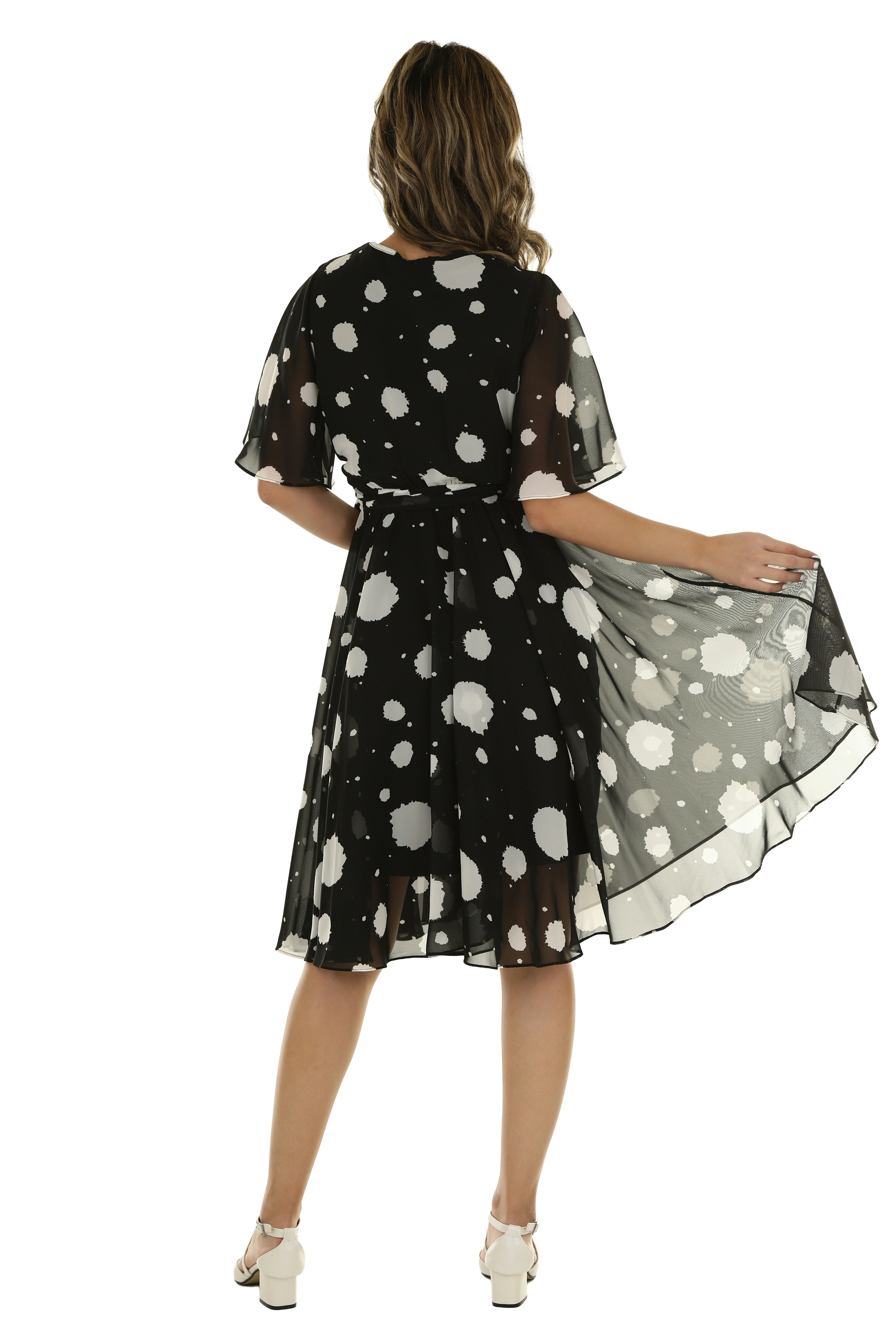 A woman in a black dress with white polka dots holding the skirt