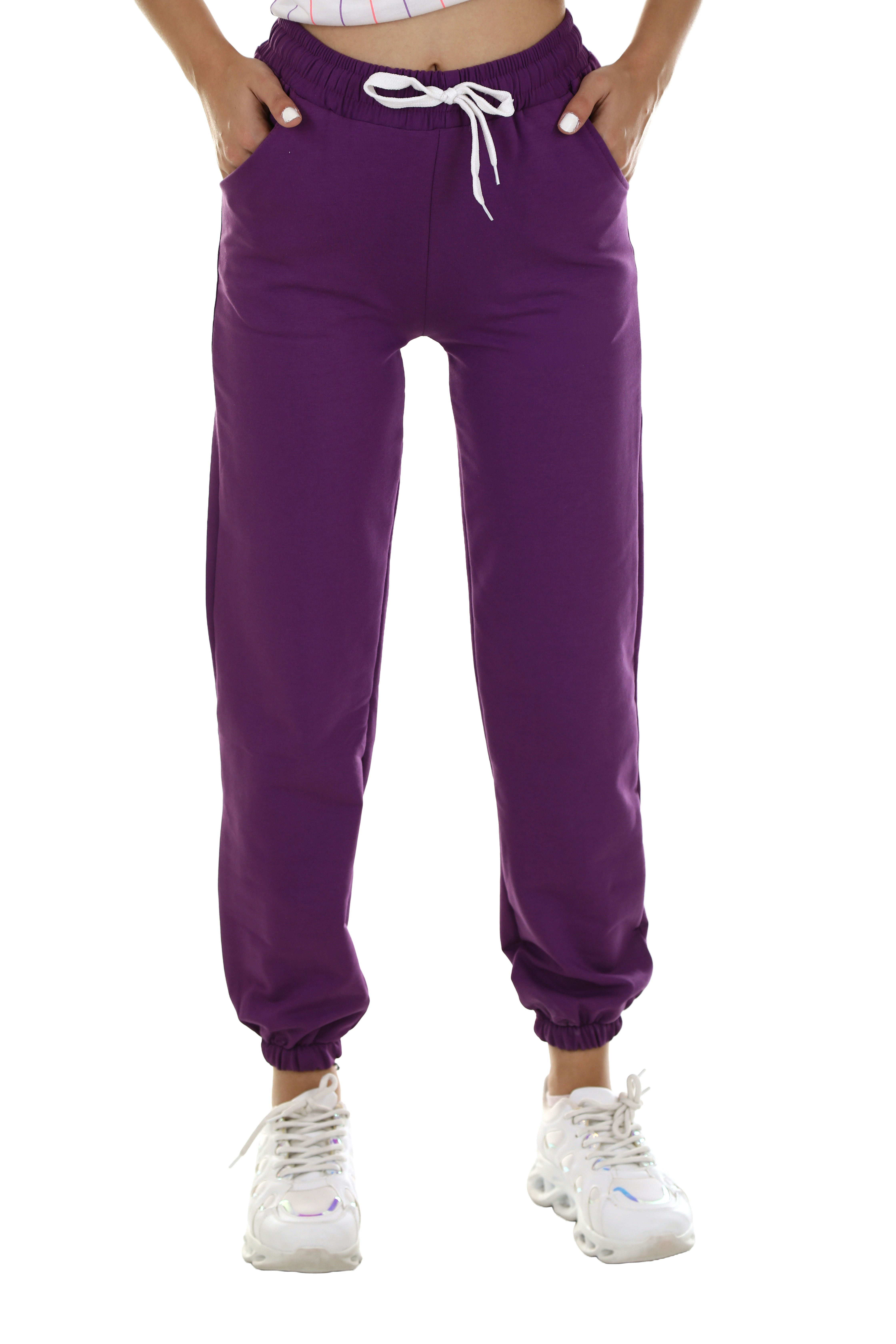 A person wearing purple sweatpants with a white drawstring and white sneakers