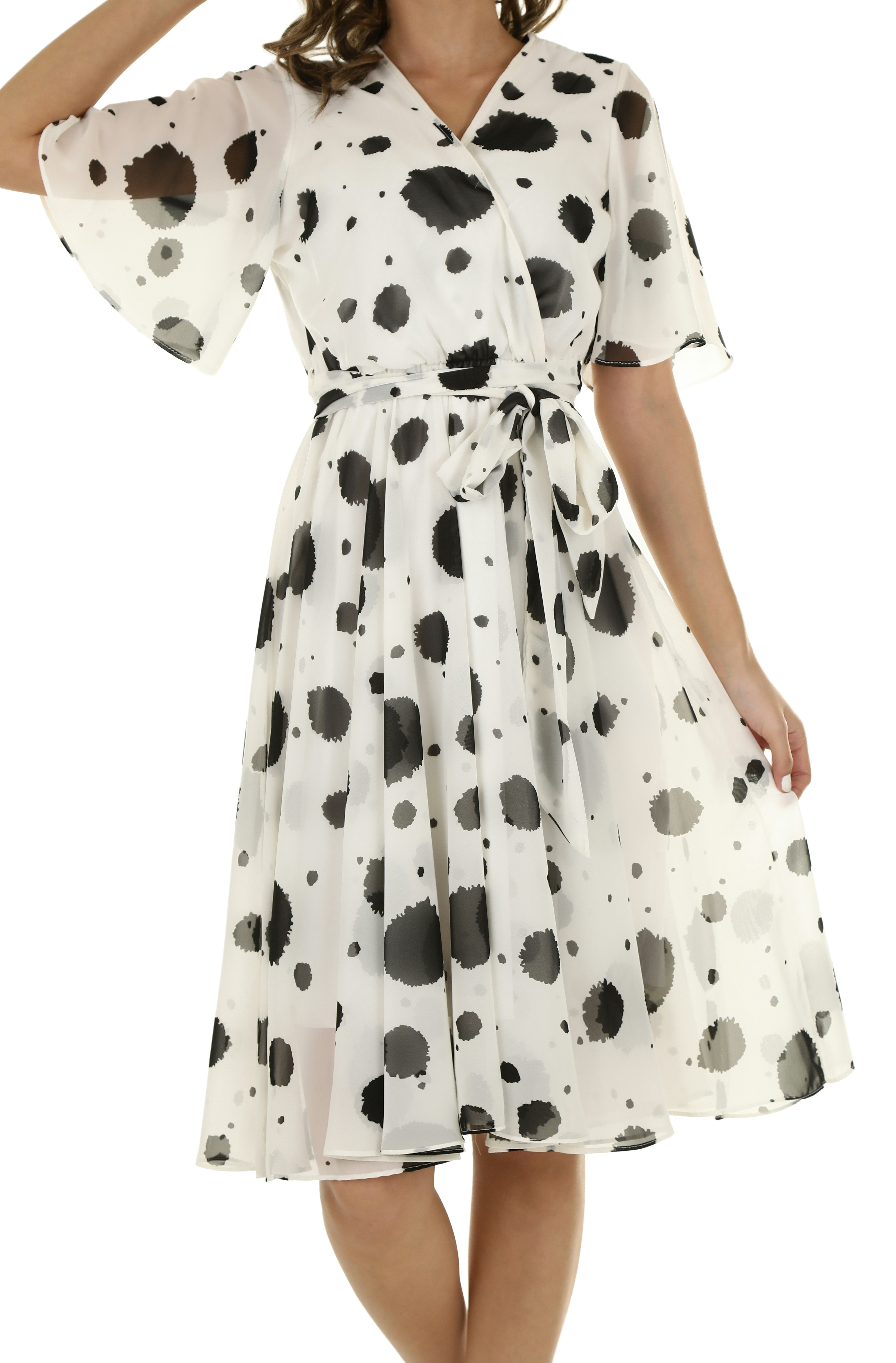 A woman wearing a white wrap dress with black ink blot patterns