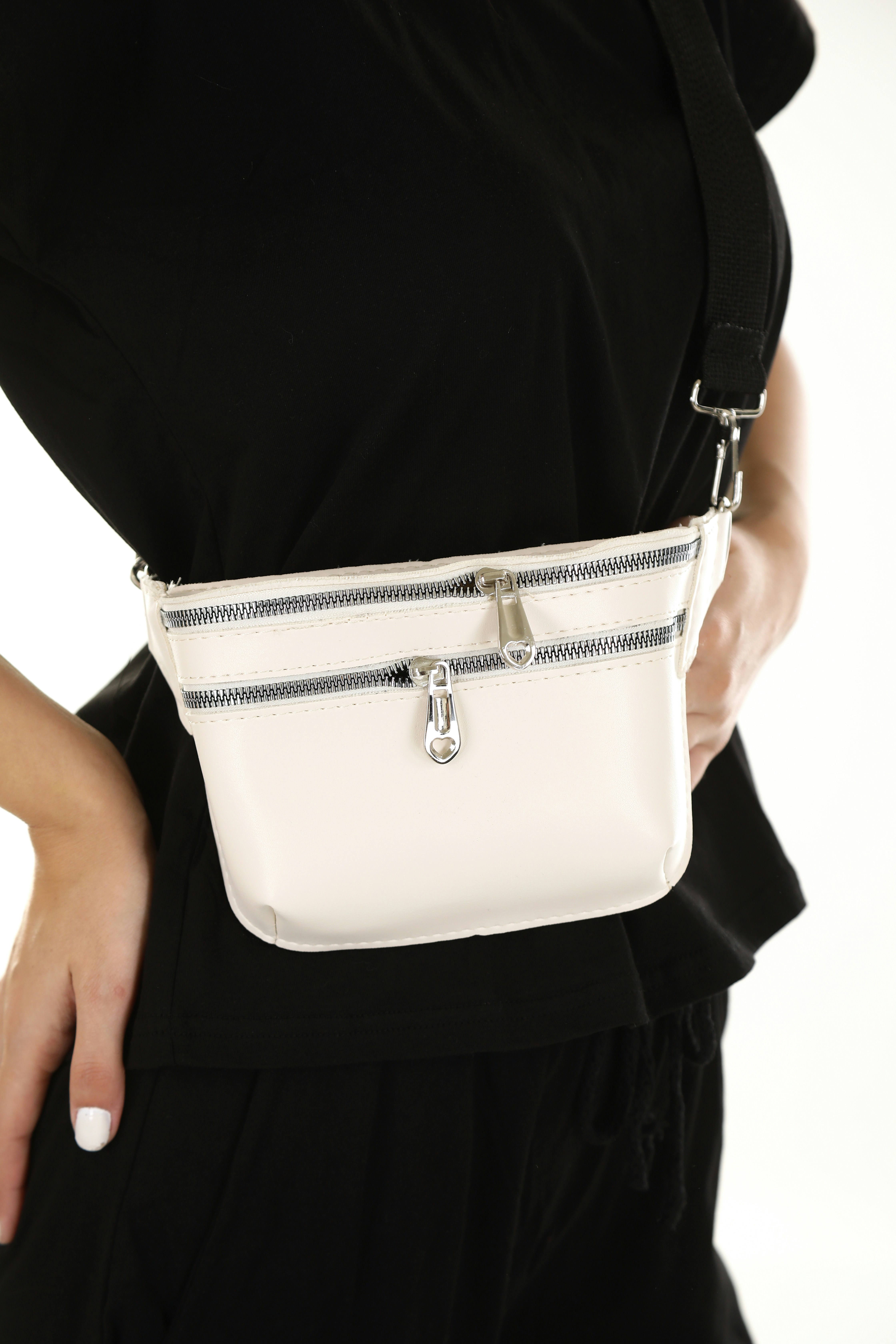 Close-up of a white belt bag with two zips worn at the hip over a black T-shirt