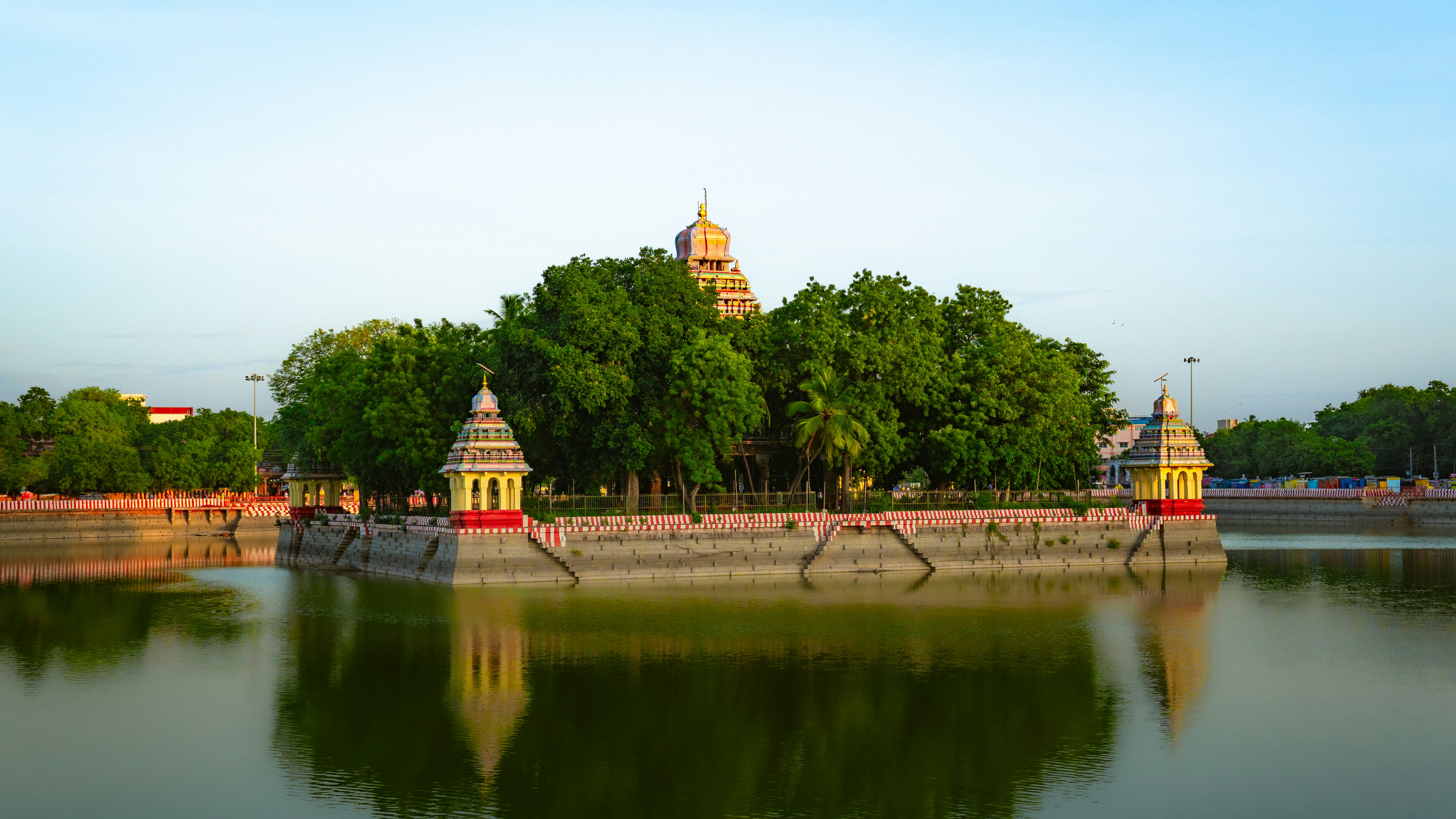 A Hindu temple on an island in a calm pond surrounded by trees