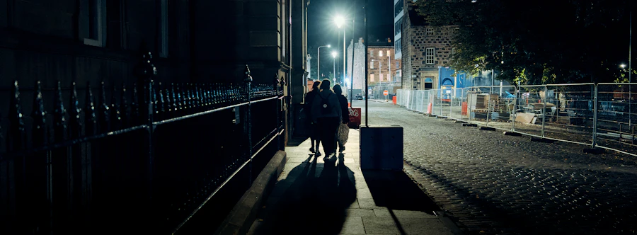Three people walking along a cobbled street under lamps