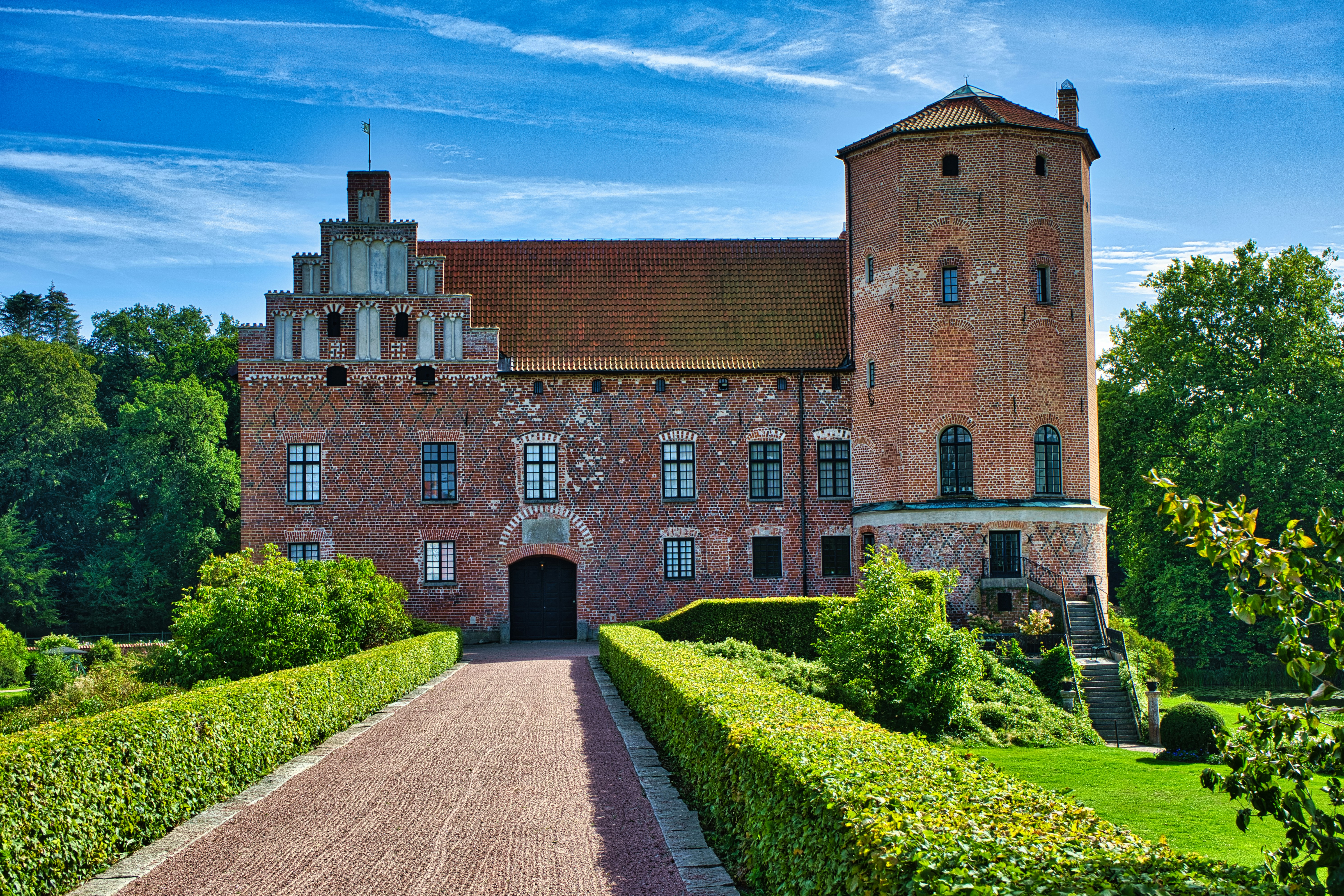 A red brick castle with a tall round tower and a stepped gable roof