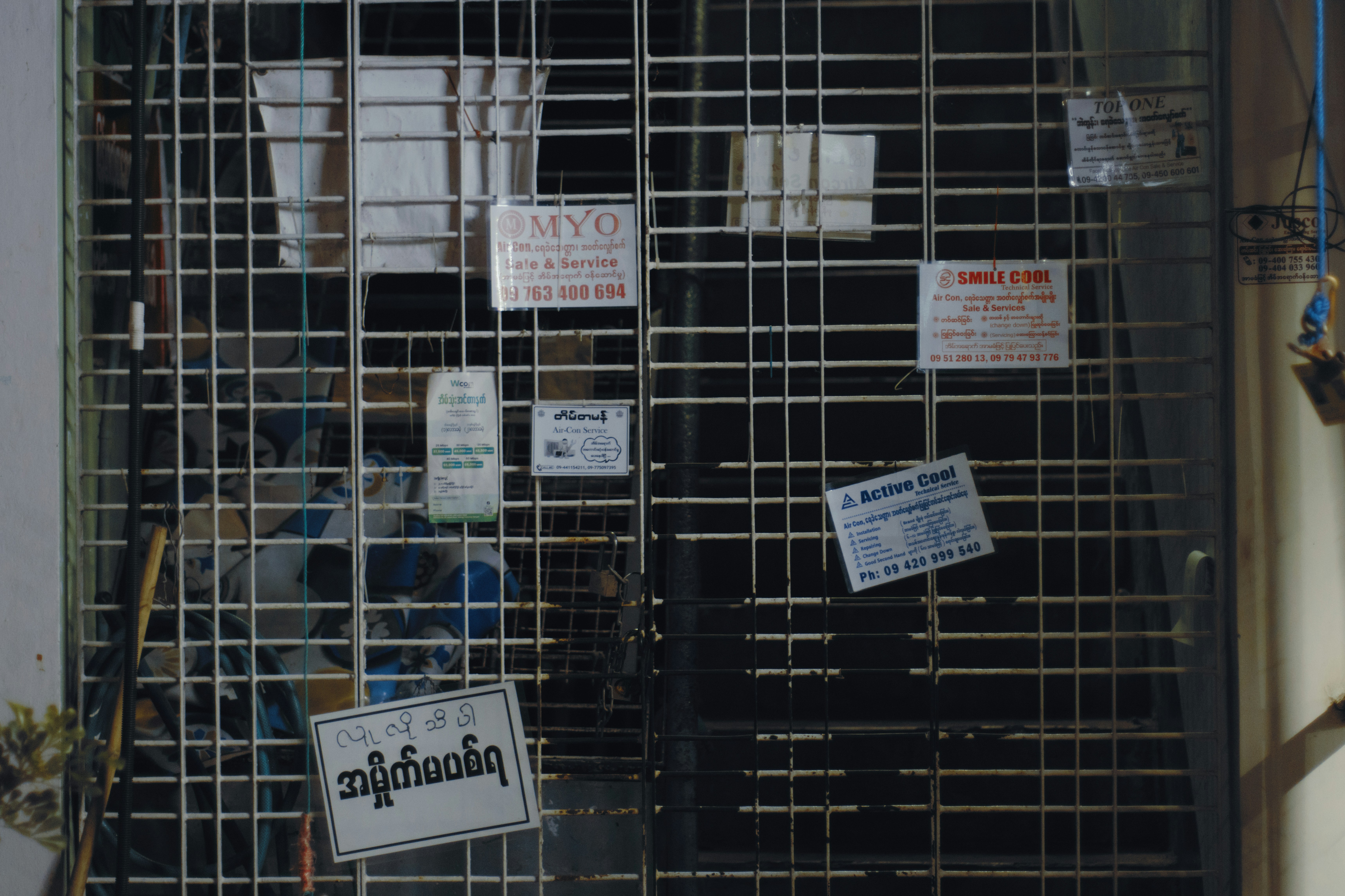 A white metal security gate covered in various small business service advertisements