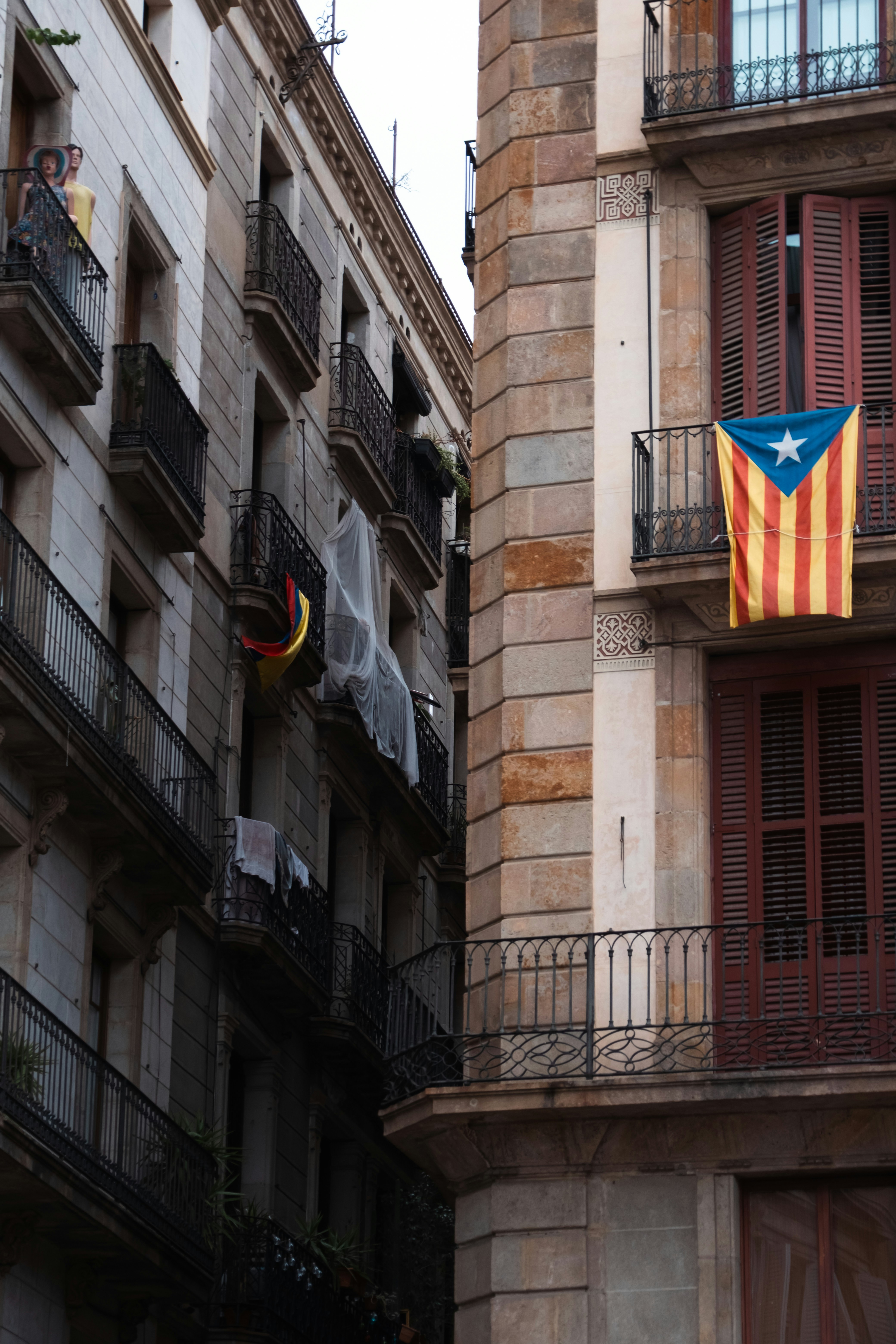 Stone apartment buildings with balconies and hanging flags in Barcelona