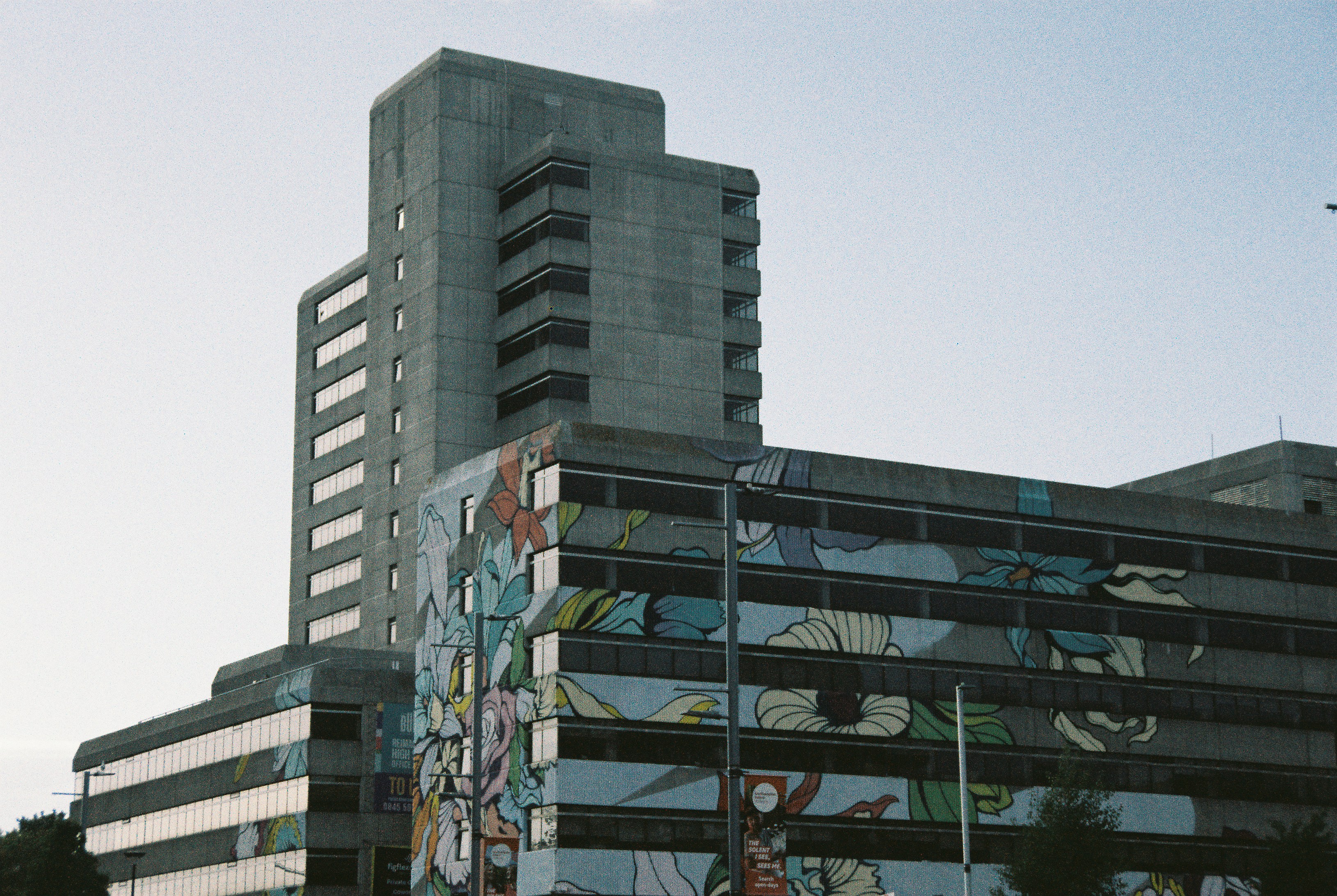 A tall concrete building with a large floral mural on its facade
