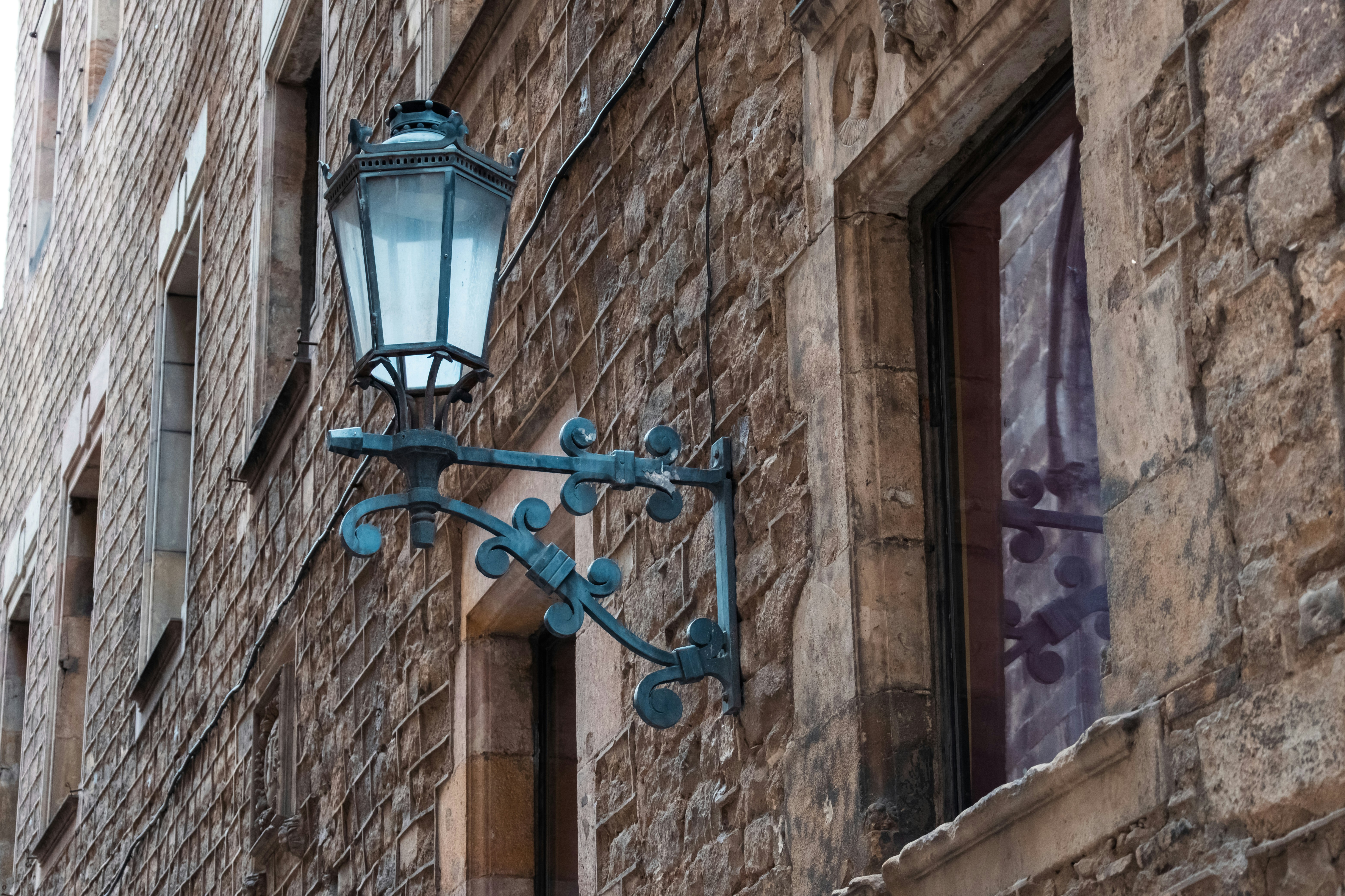An ornate metal lantern mounted on a rustic stone wall in Barcelona
