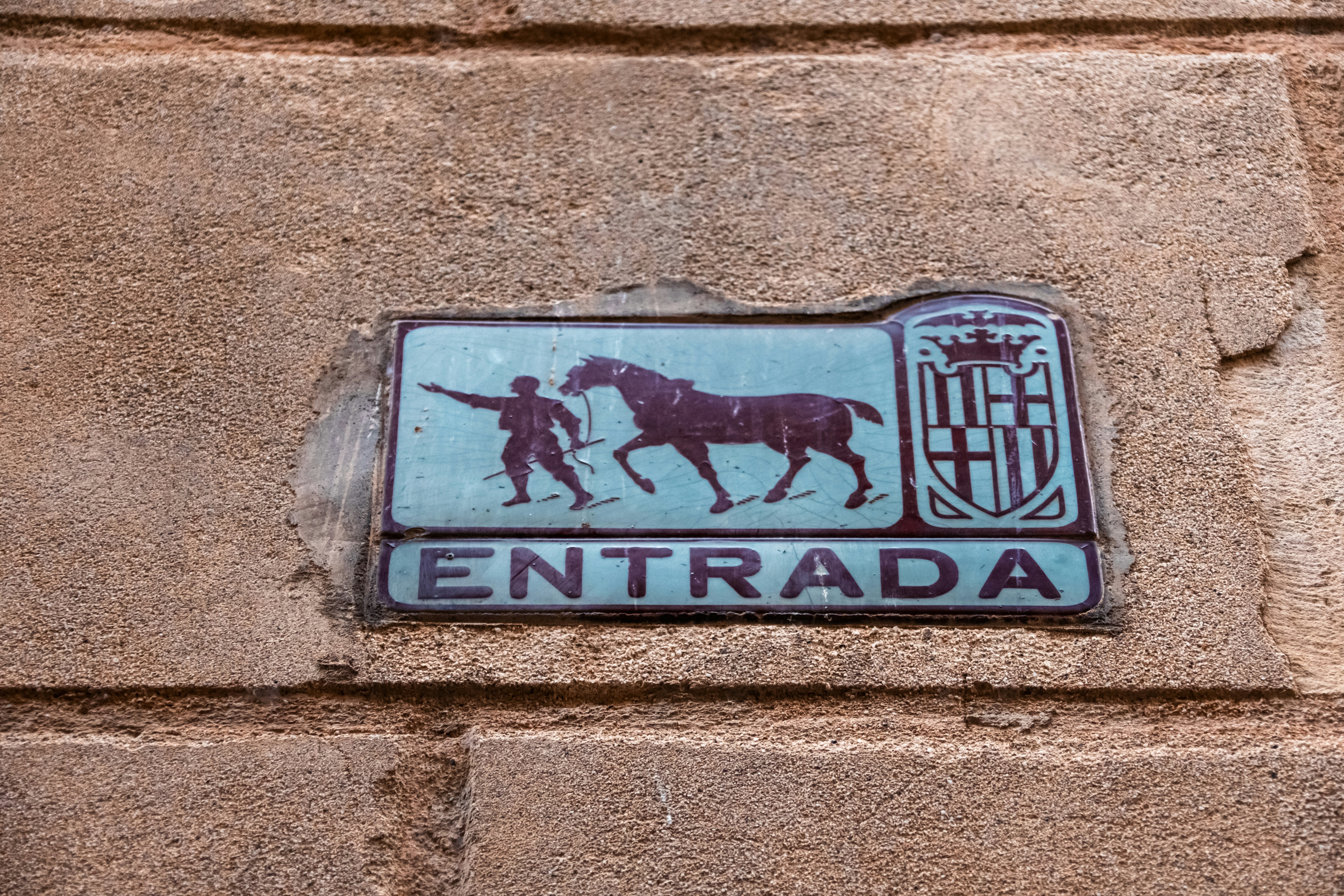 A ceramic tile sign reading ENTRADA with a silhouette of a person and horse