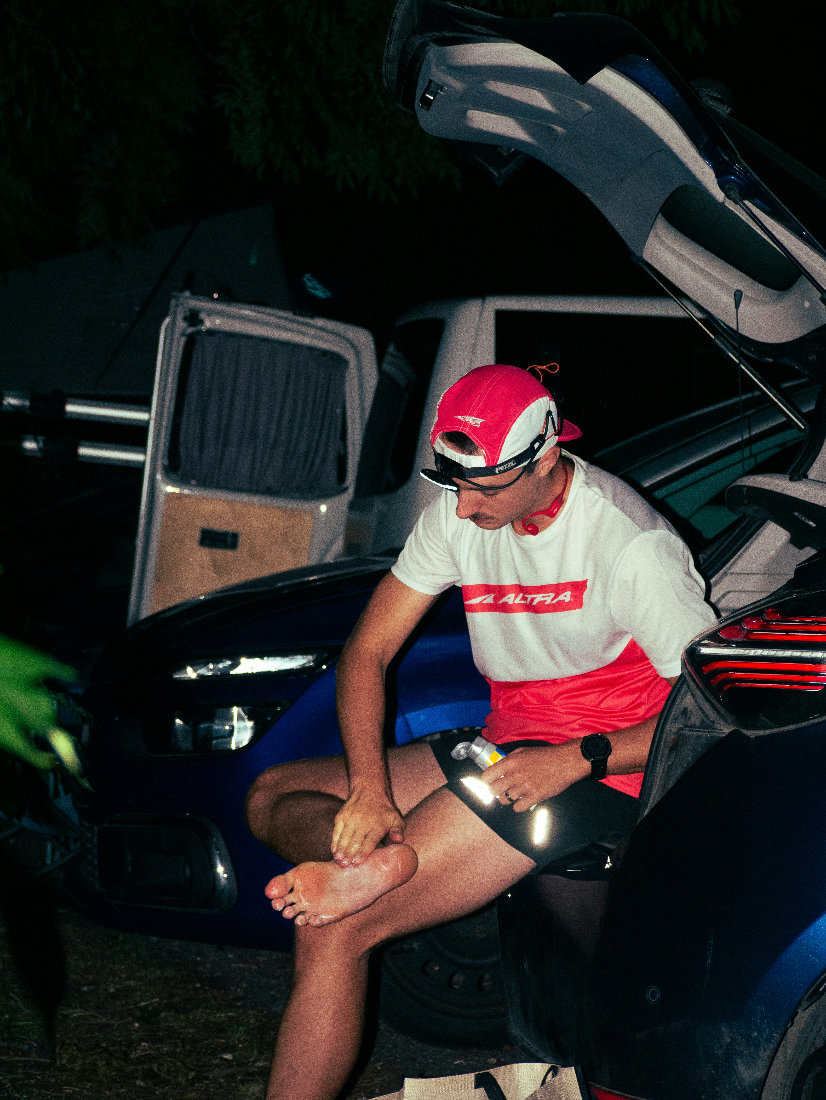 A person in a red and white shirt applying cream to their foot