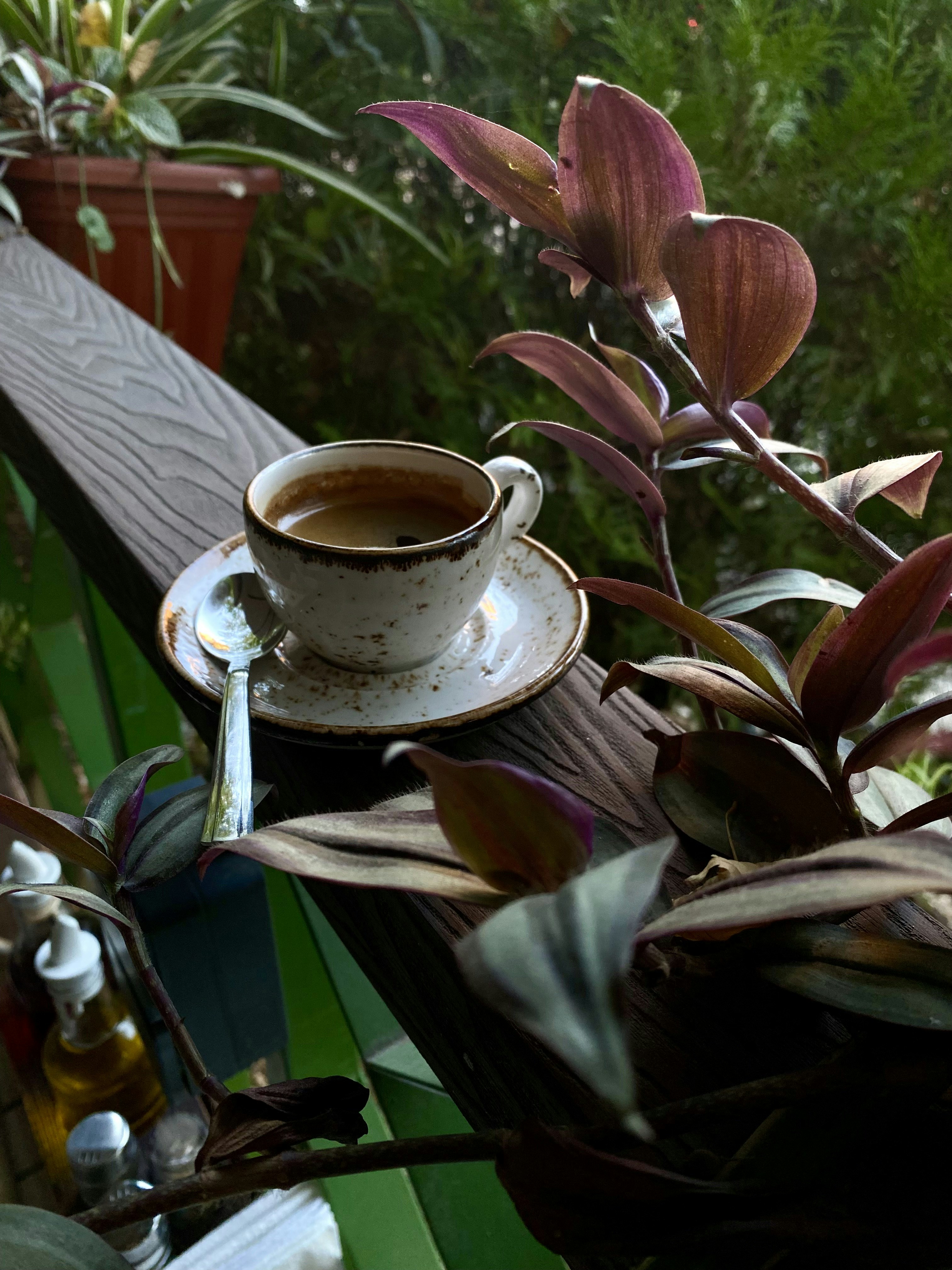 Une tasse d’espresso sur une soucoupe avec une cuillère posée sur une rambarde en bois