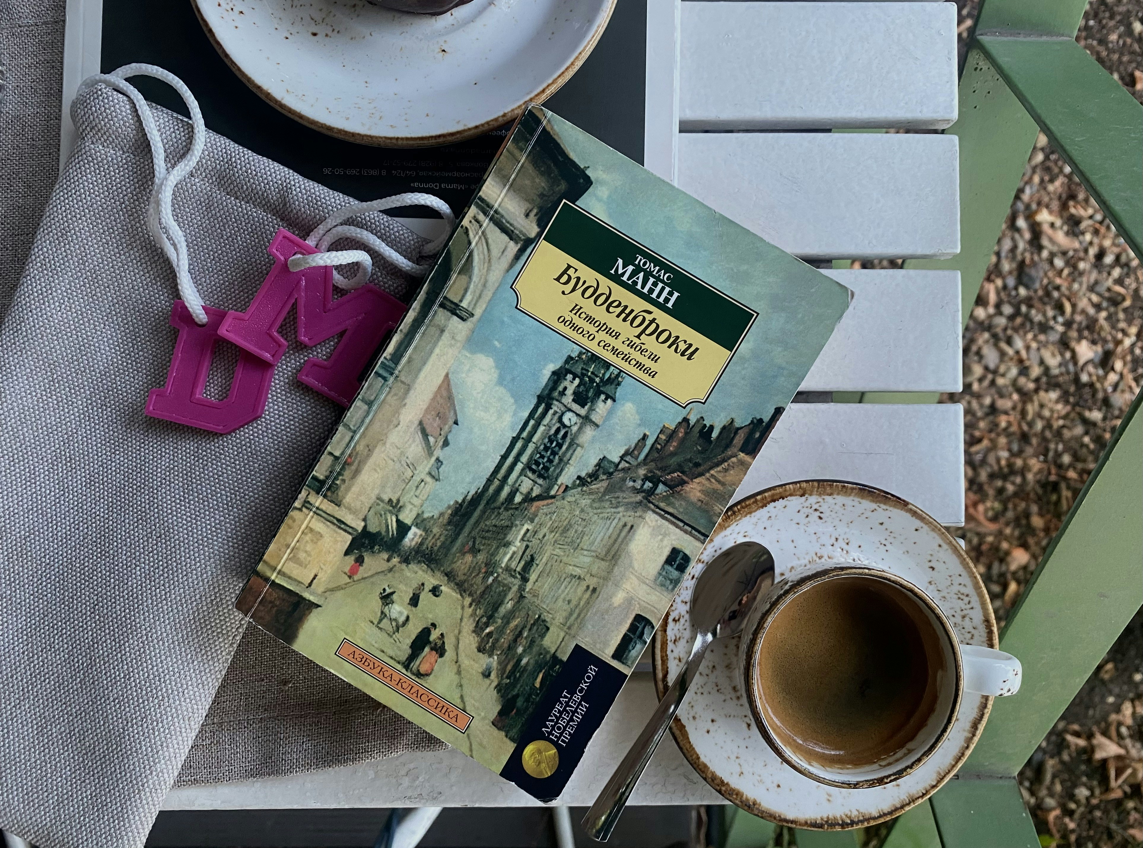 Un livre avec une peinture sur la couverture à côté d’une tasse de café et d’un sachet