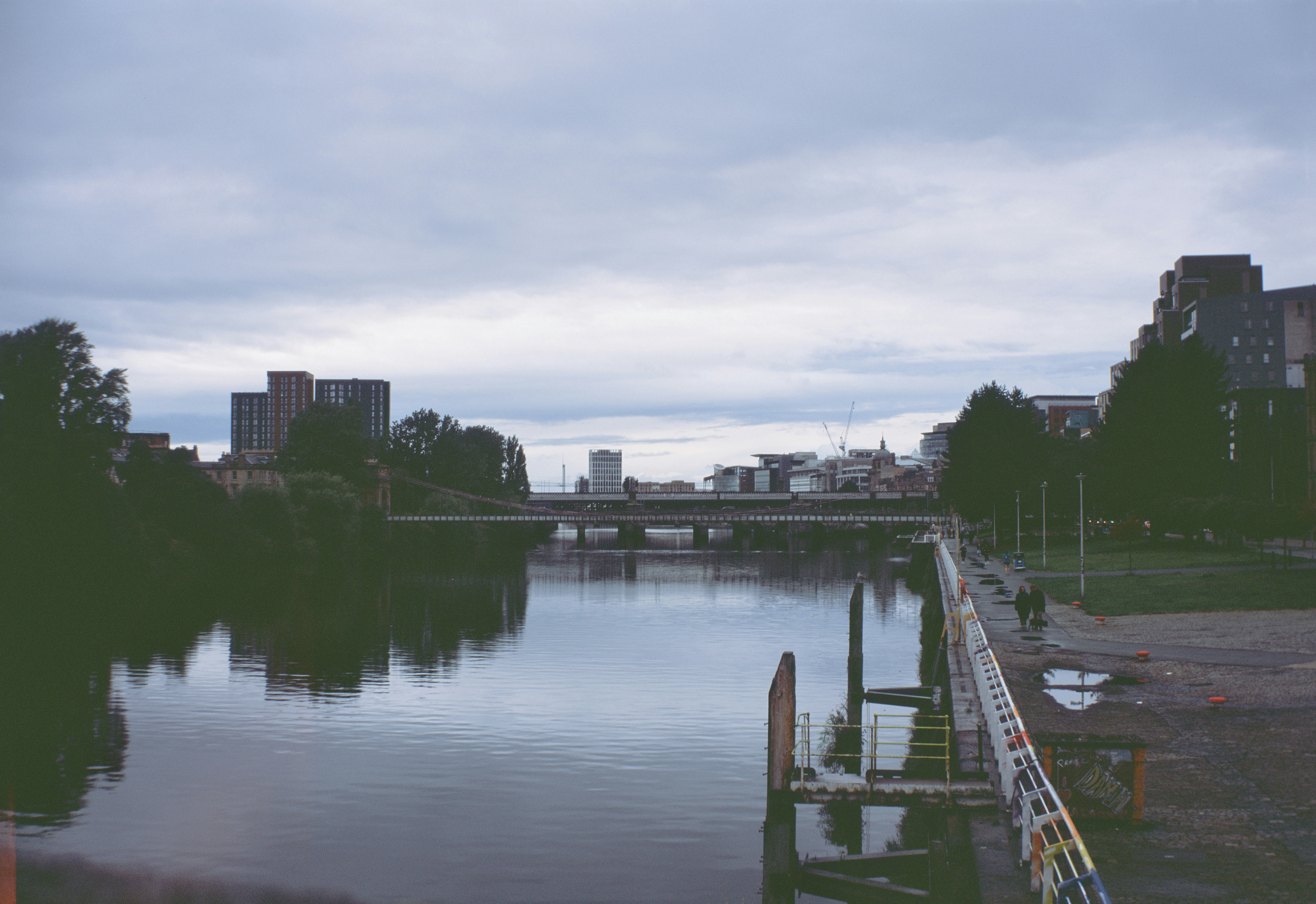 The River Clyde flowing past buildings and bridges in Glasgow under a cloudy sky