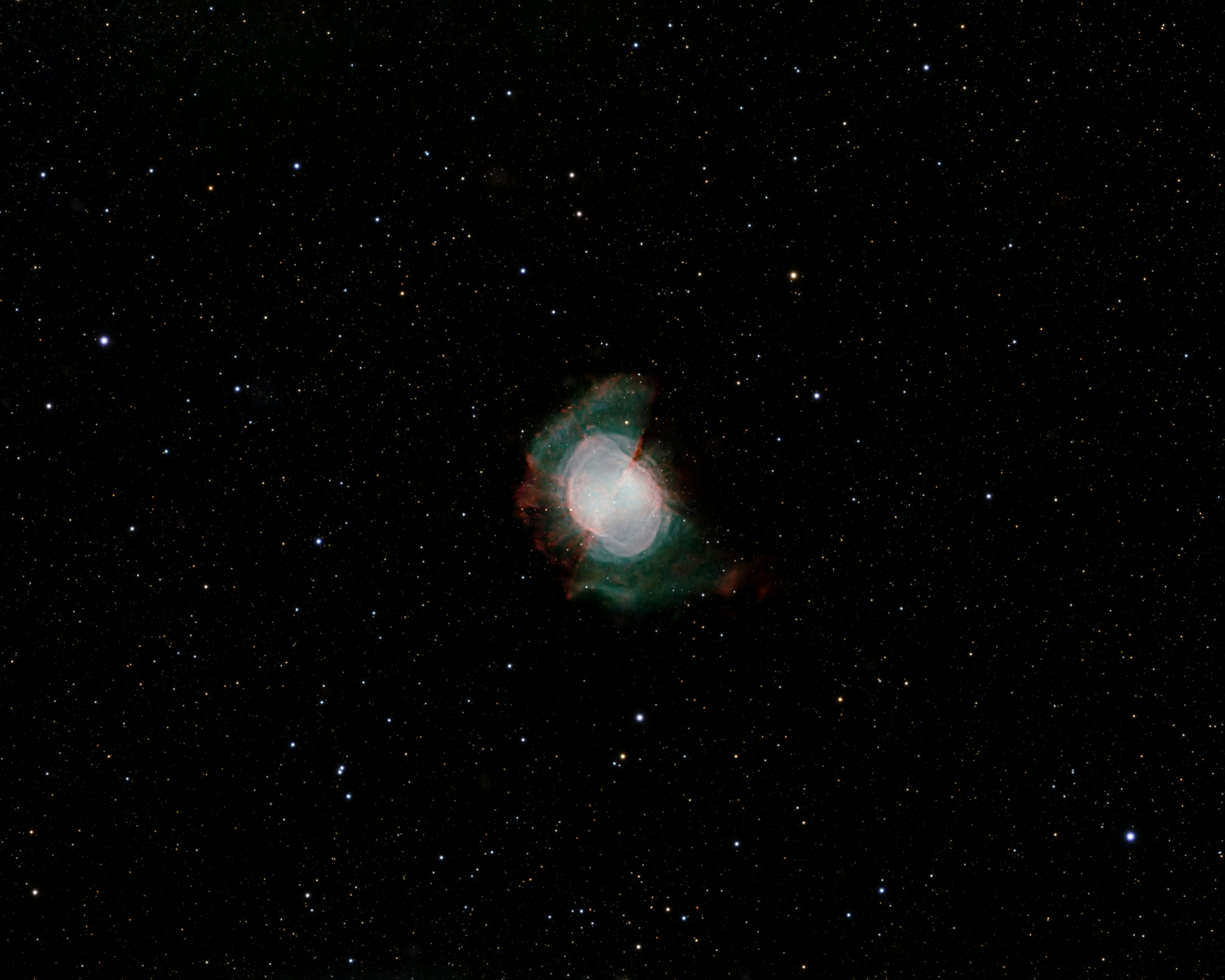 The Dumbbell Nebula glowing with green and red light among scattered stars