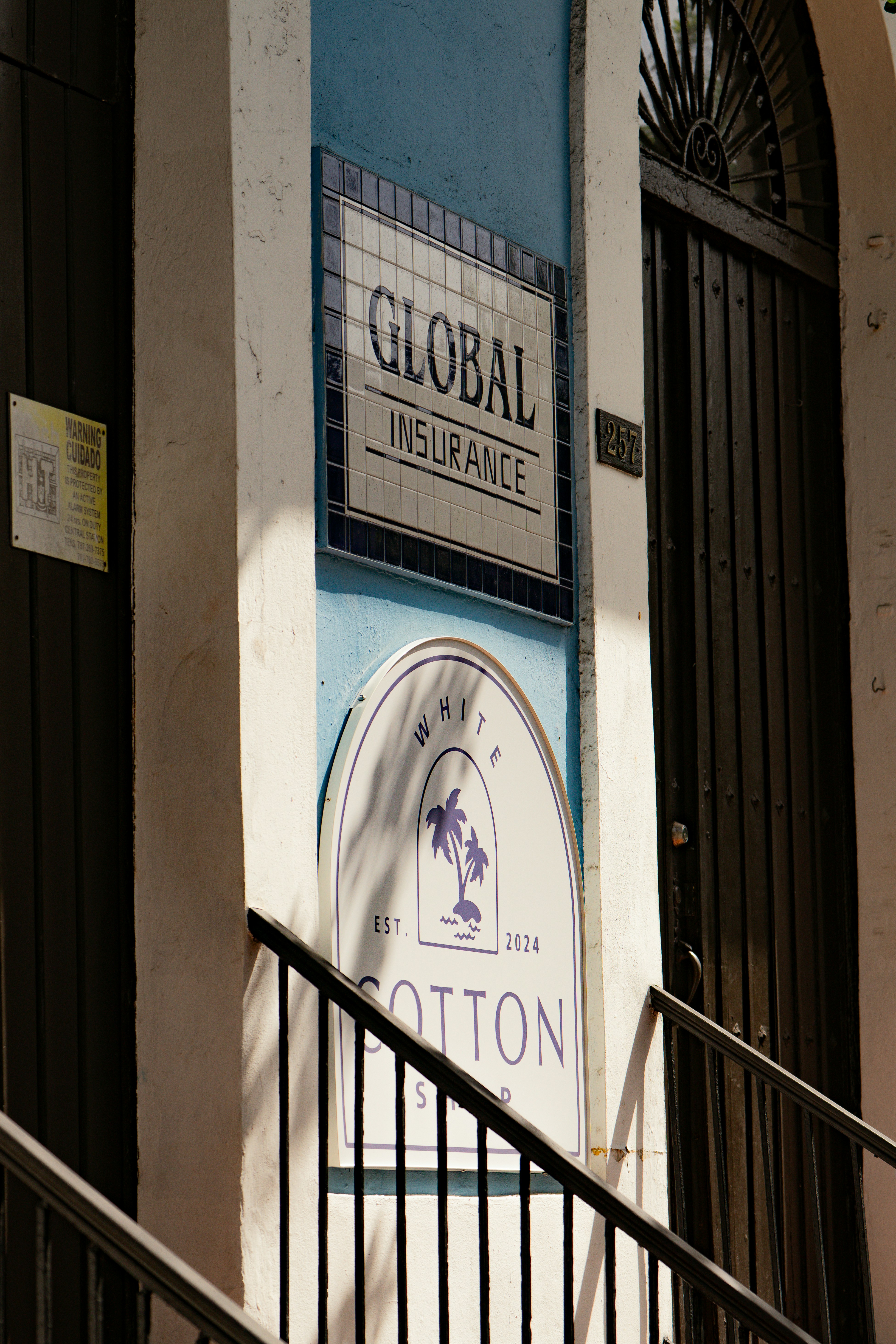 Signs for Global Insurance and White Cotton Shop on a blue building exterior