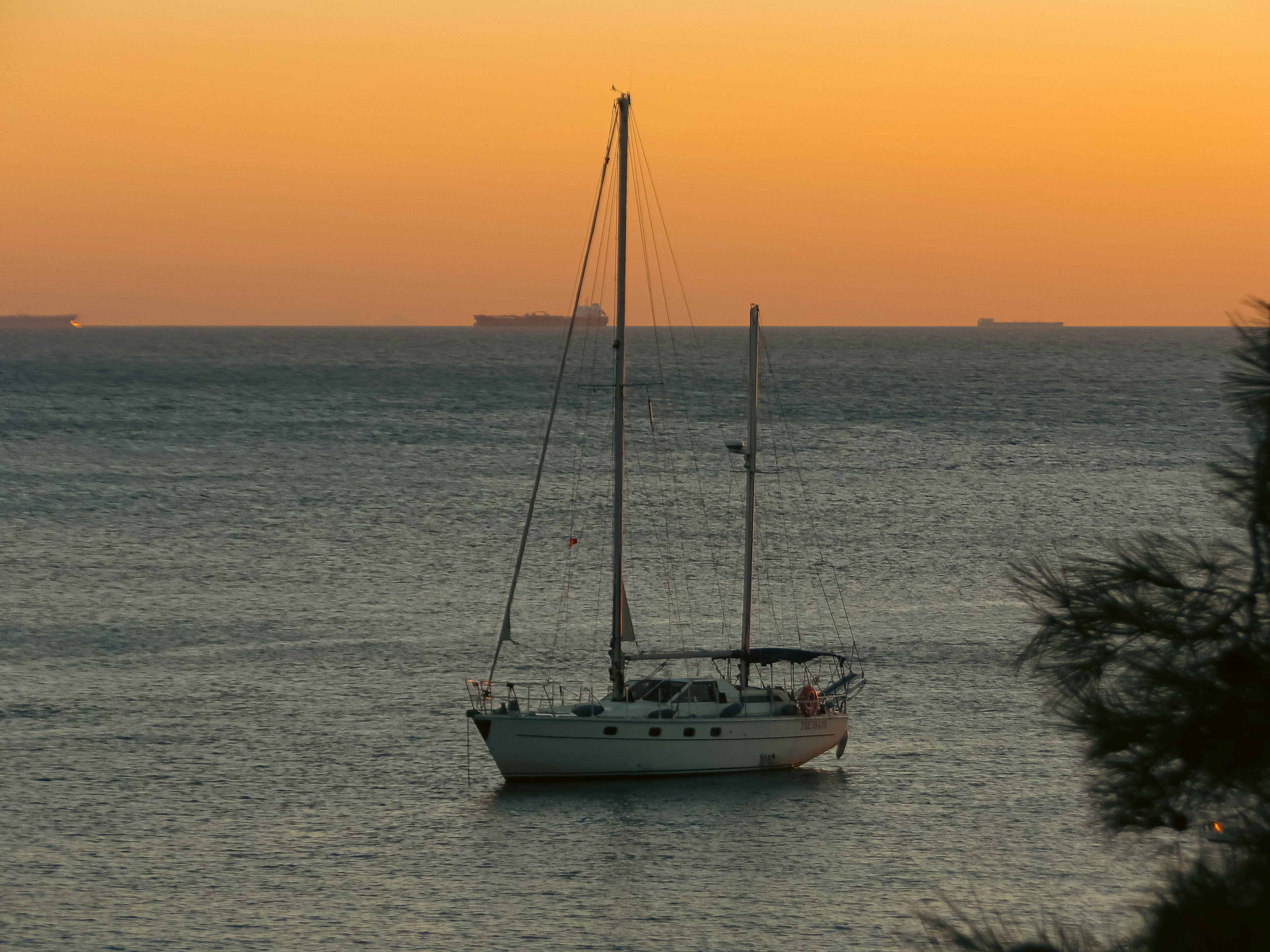 Un velero blanco en el mar bajo un cielo naranja cálido a la hora dorada