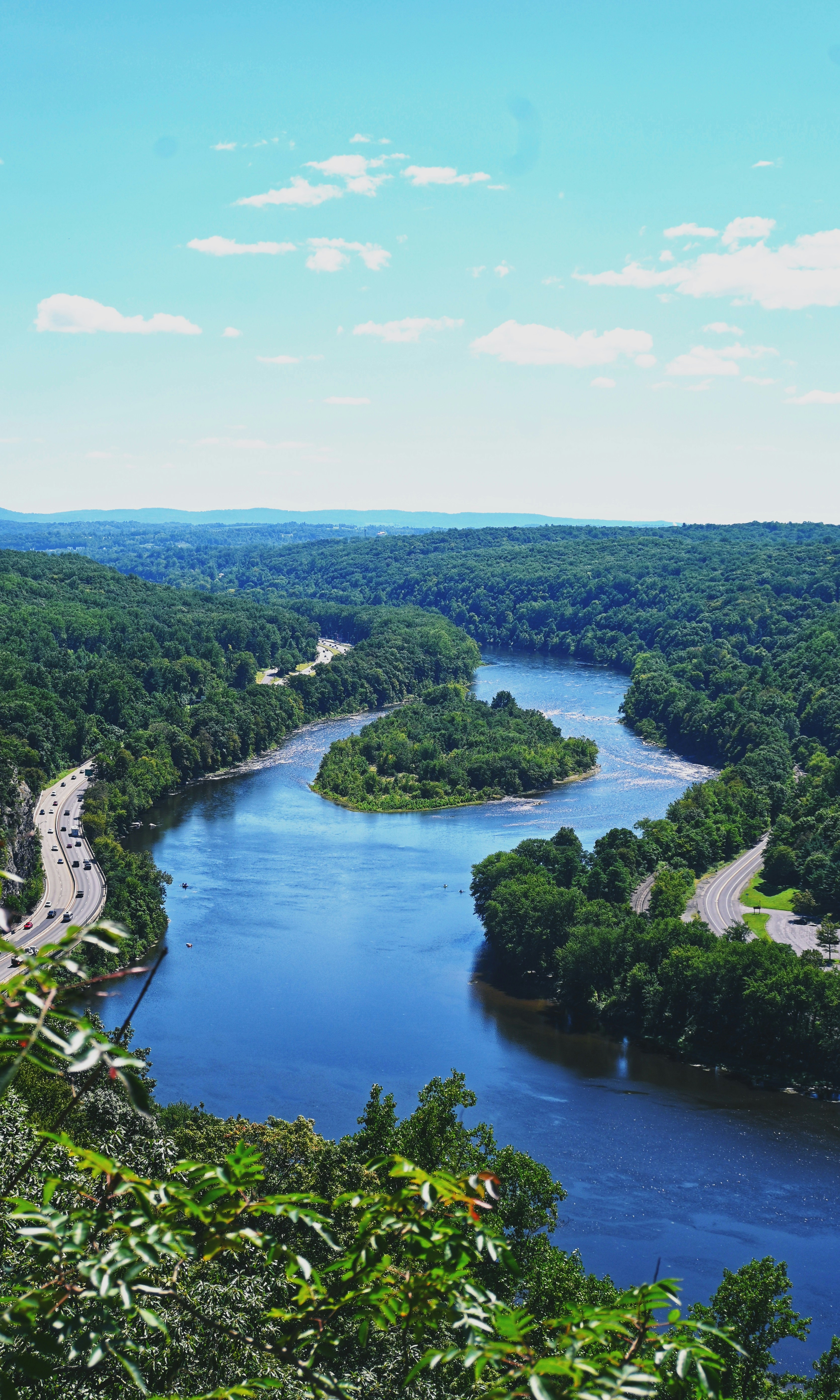 A winding river flowing through a lush green valley with a highway nearby