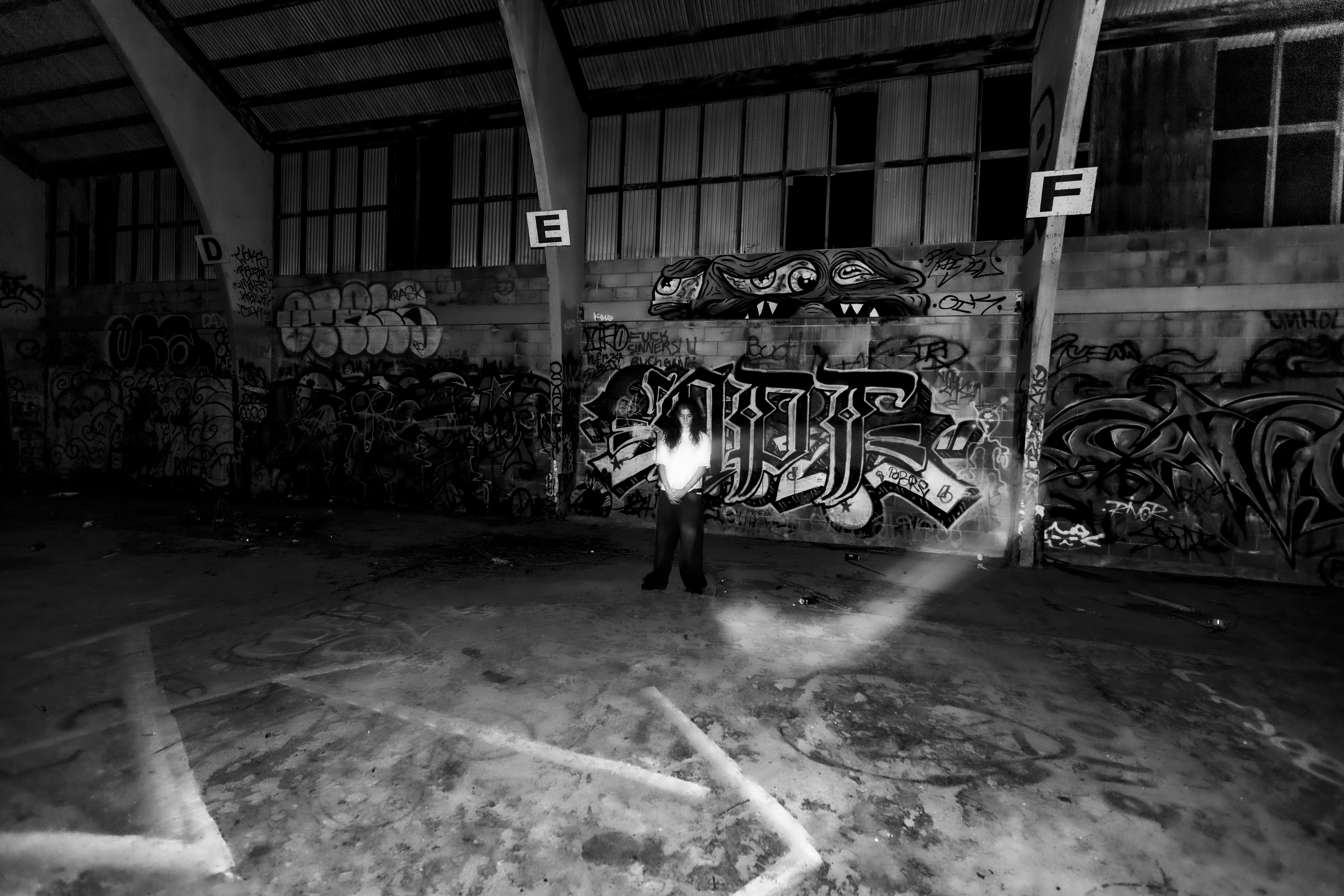 A person in a light shirt standing before a graffiti covered wall