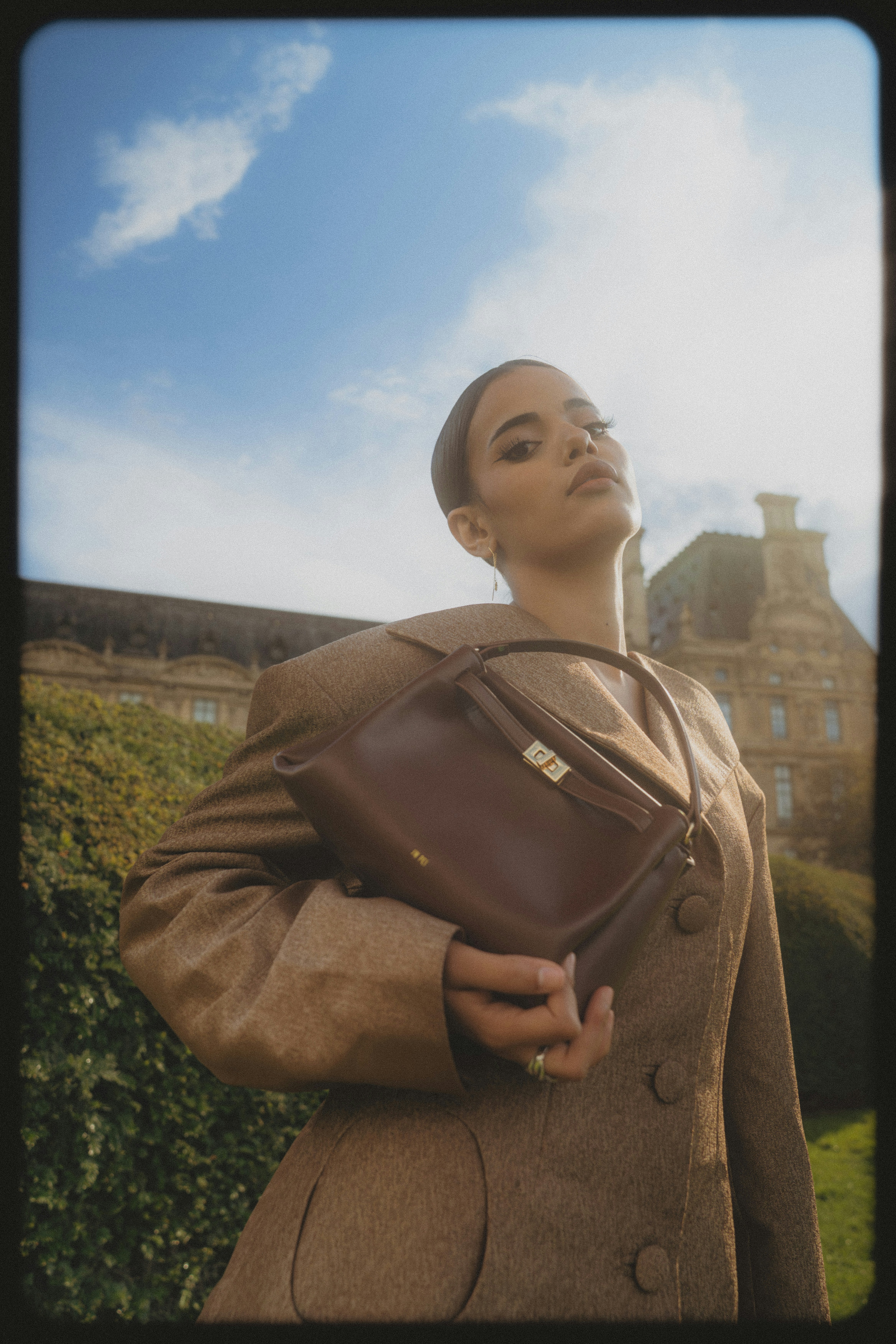 A woman in a brown blazer holding a brown leather handbag in Paris