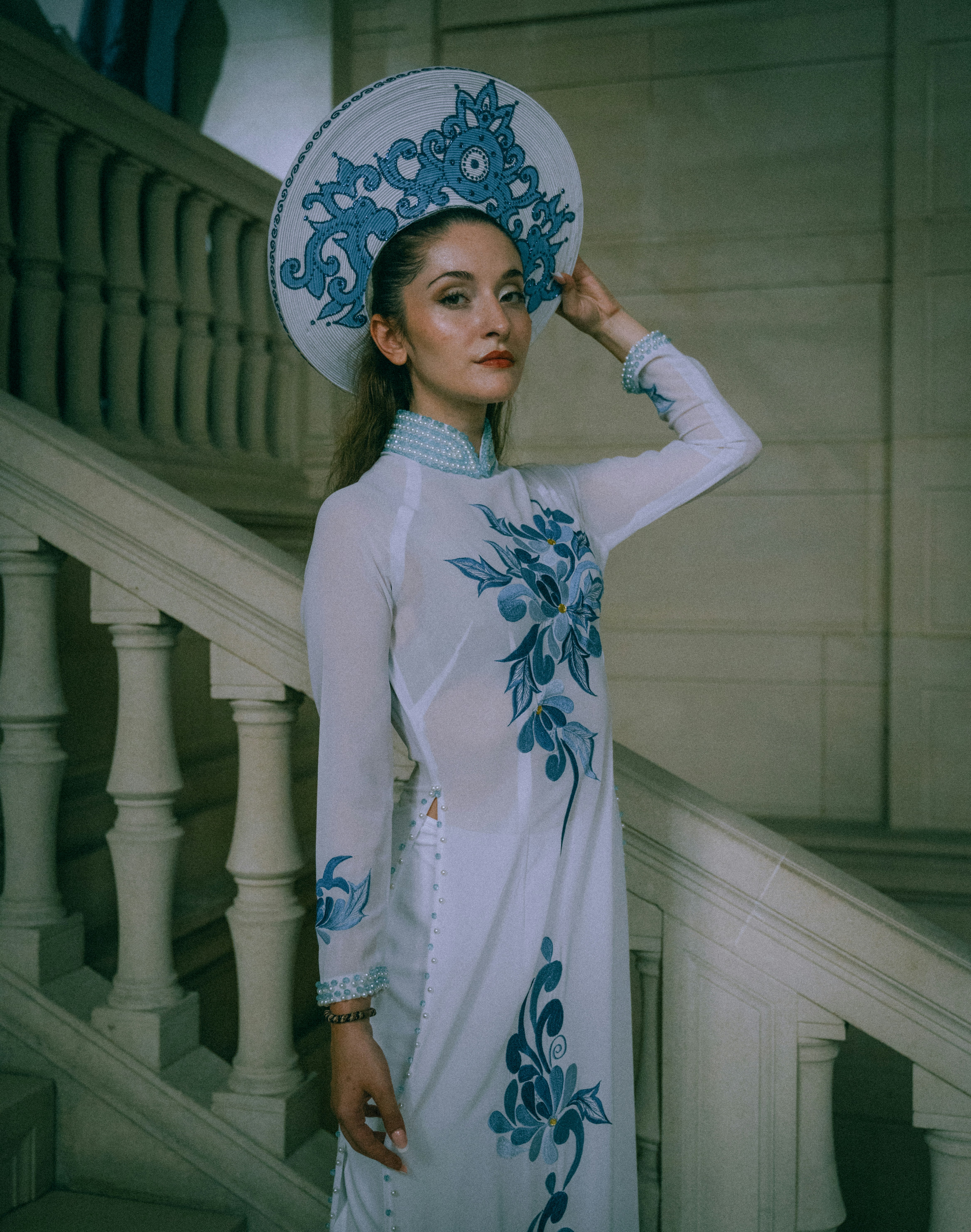 A woman wearing a white and blue ao dai with a matching headpiece