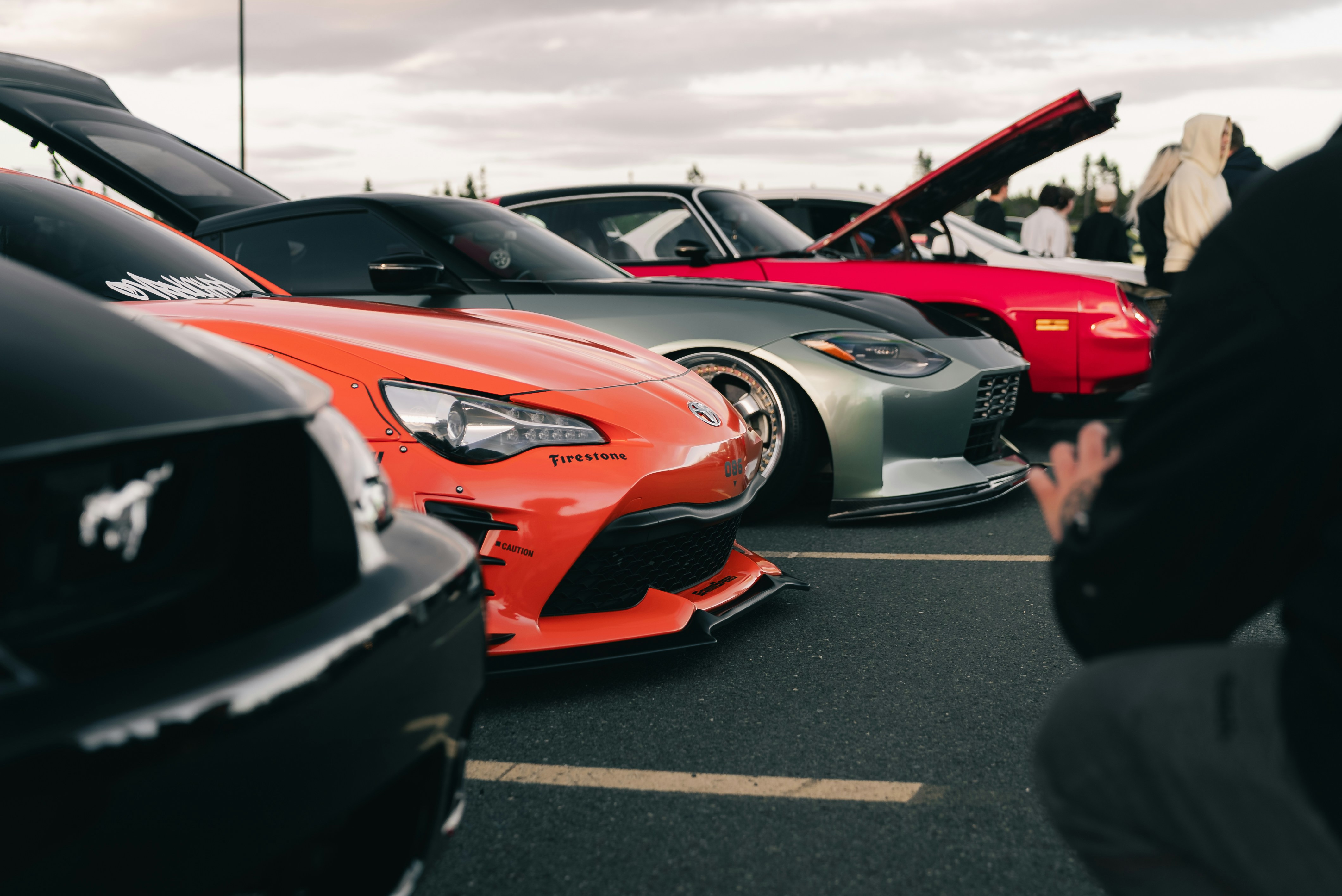 Modified sports cars parked in a row at an outdoor car show