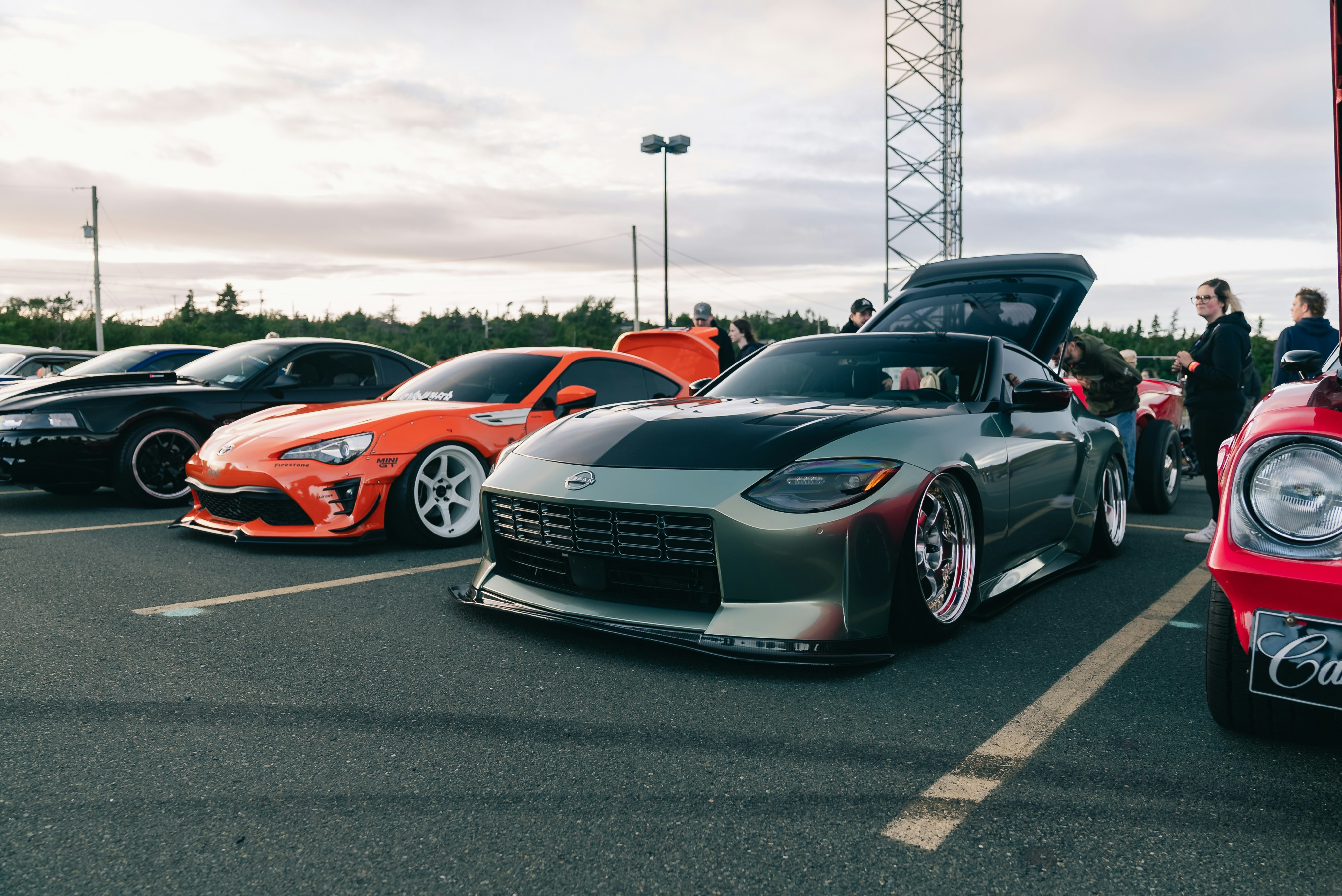 Modified sports cars parked in a row at an outdoor car show