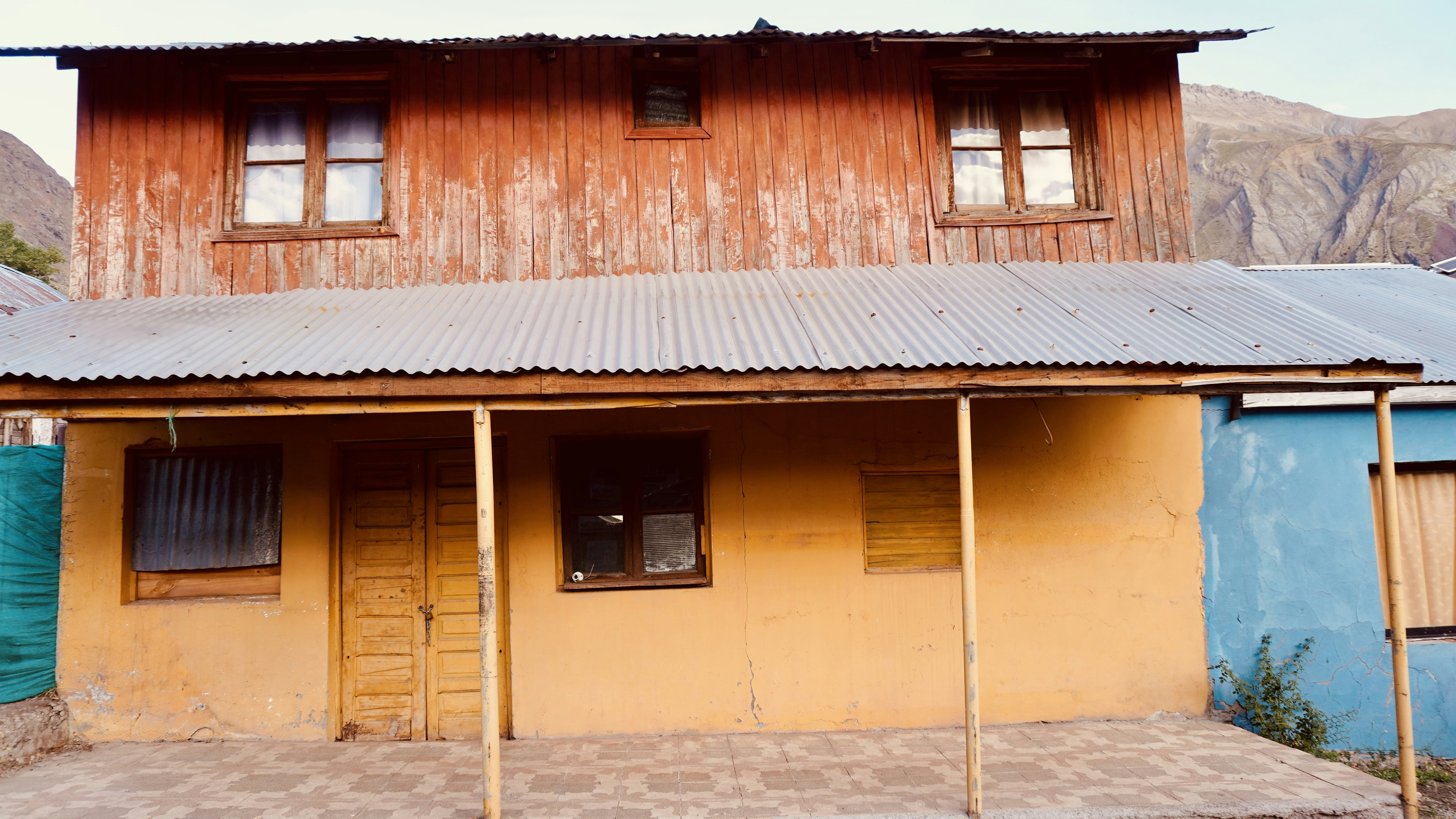 A two-story house with orange wooden siding and a yellow stucco ground floor