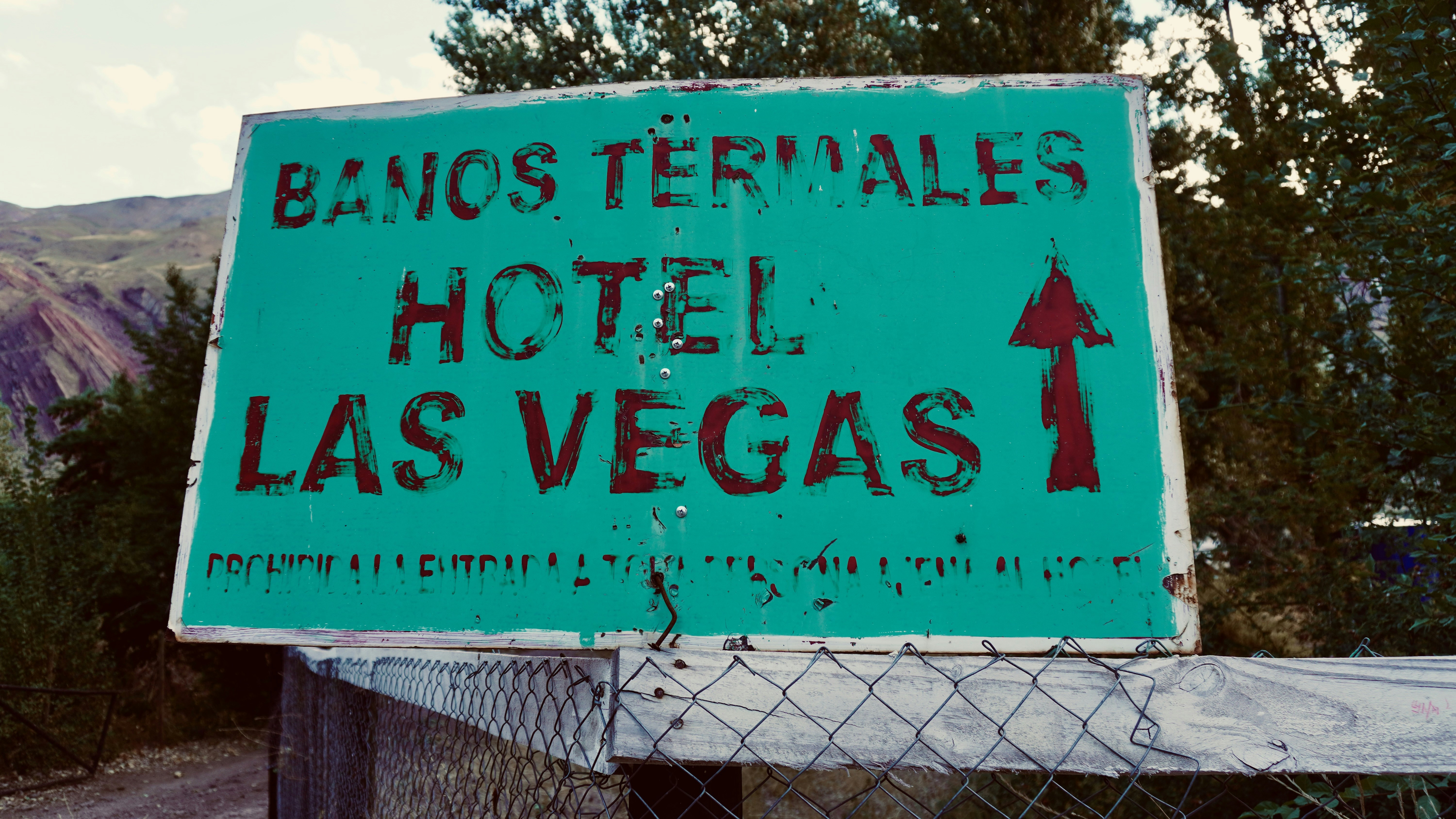 A weathered green sign reading "BANOS TERMALES HOTEL LAS VEGAS" with a red arrow