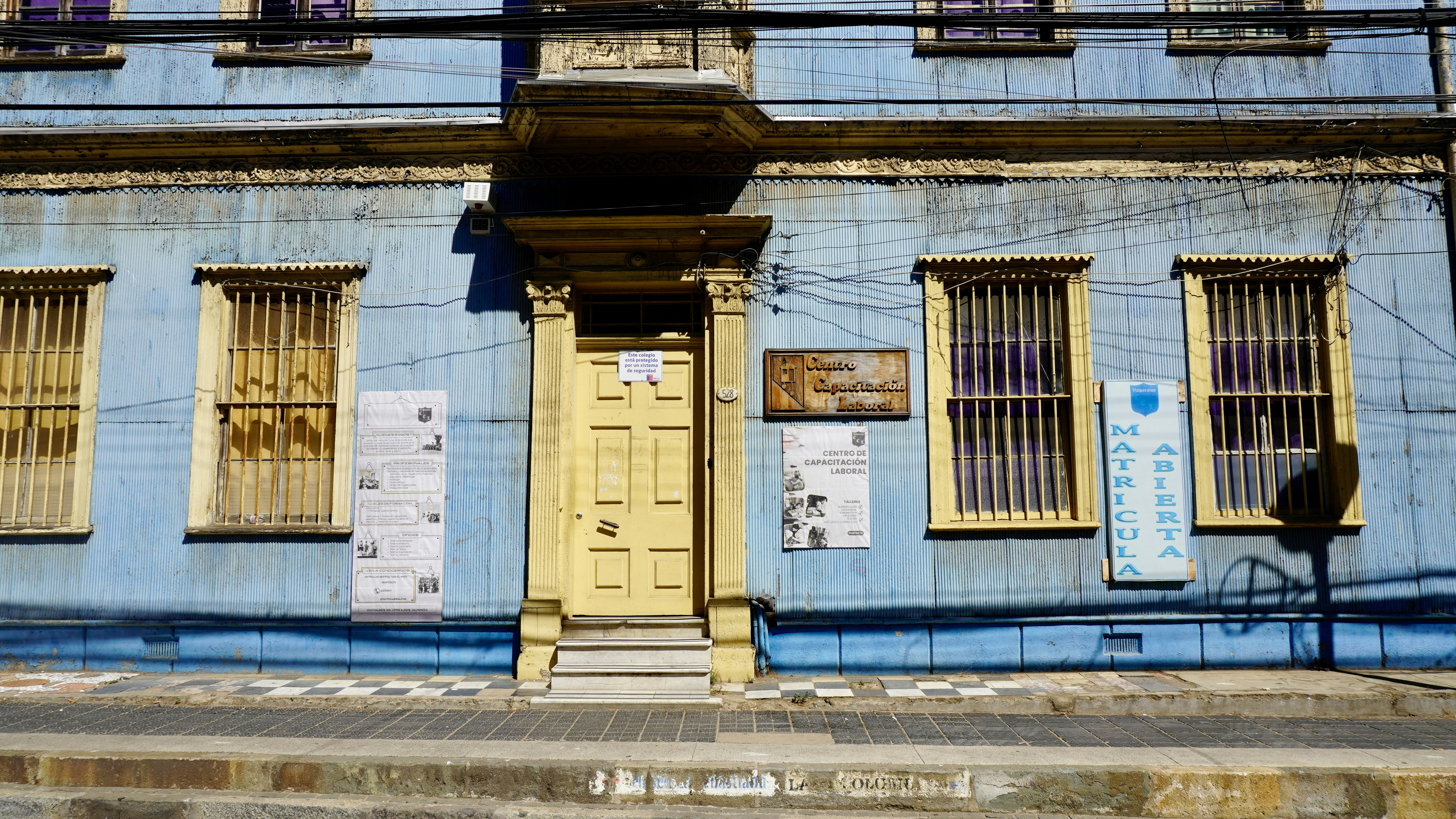 A blue building with a yellow door and windows in a city street