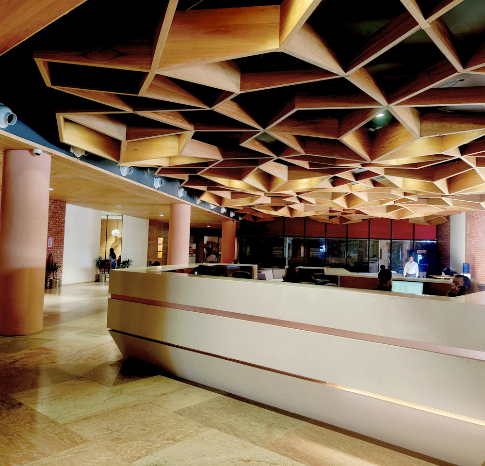 Reception desk beneath a geometric wooden ceiling