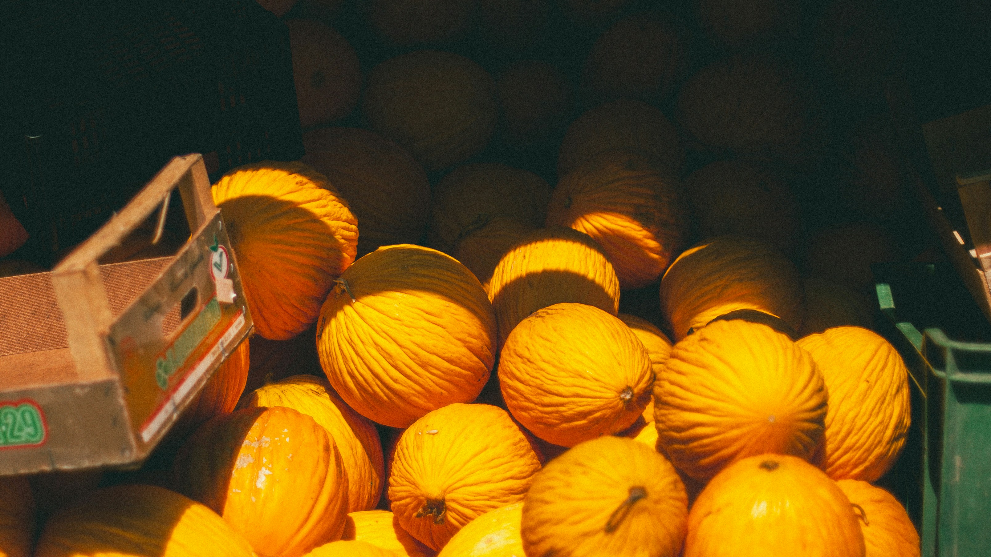 A pile of yellow melons in a wooden crate at a market in Palermo