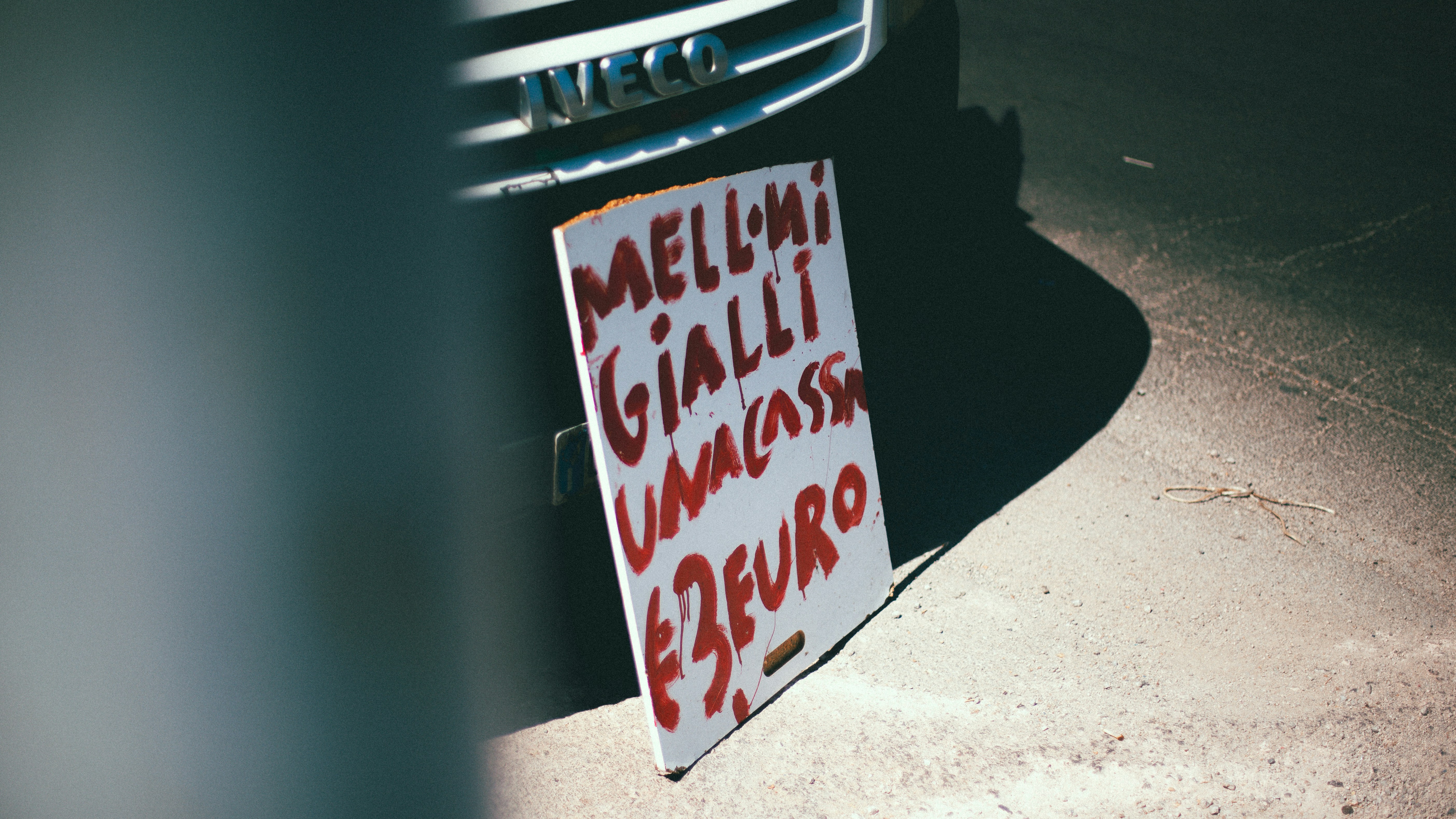 A handwritten sign with red text leaning against an Iveco van in Palermo