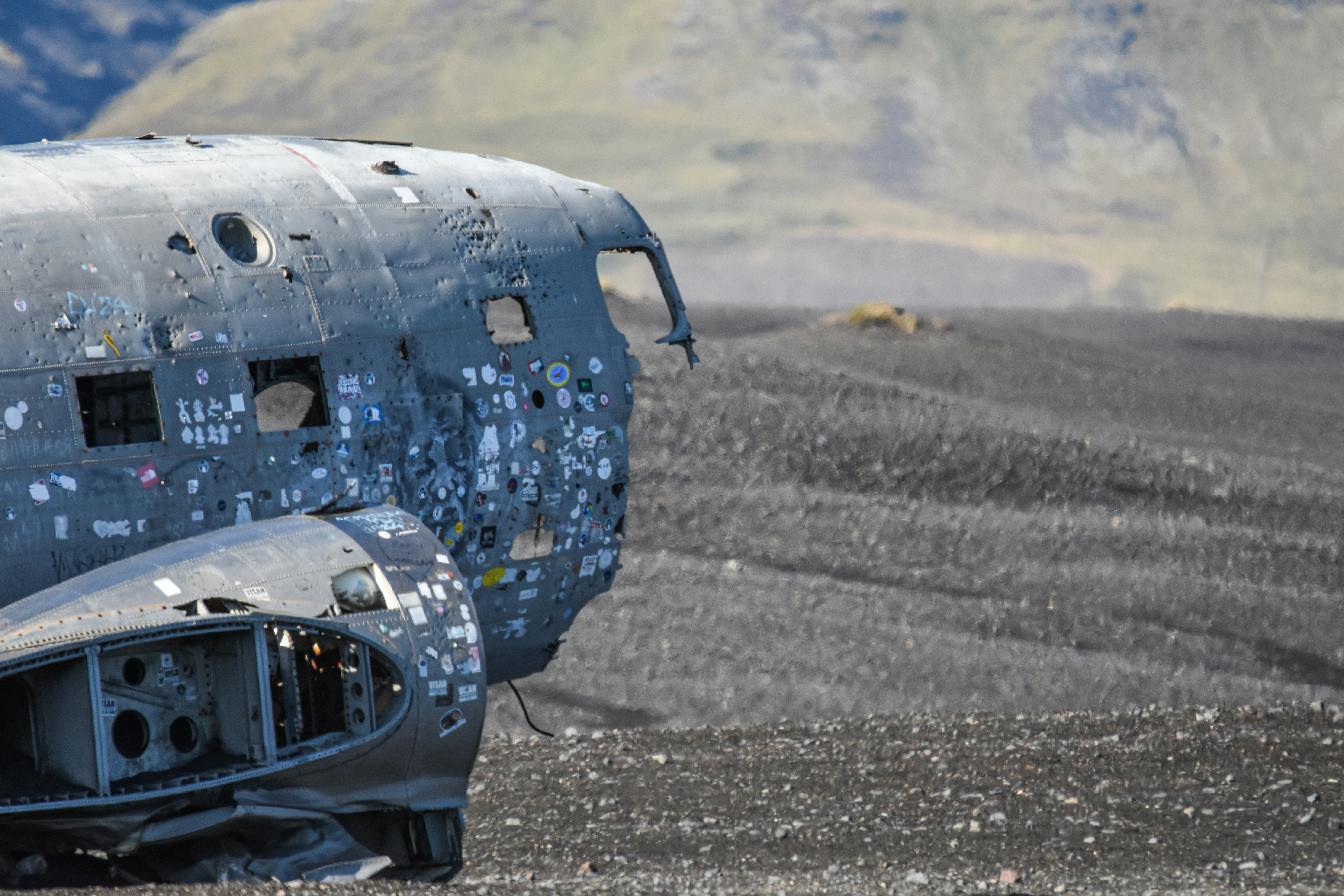 Uma fuselagem de avião desgastada coberta de adesivos sobre uma paisagem escura de areia vulcânica