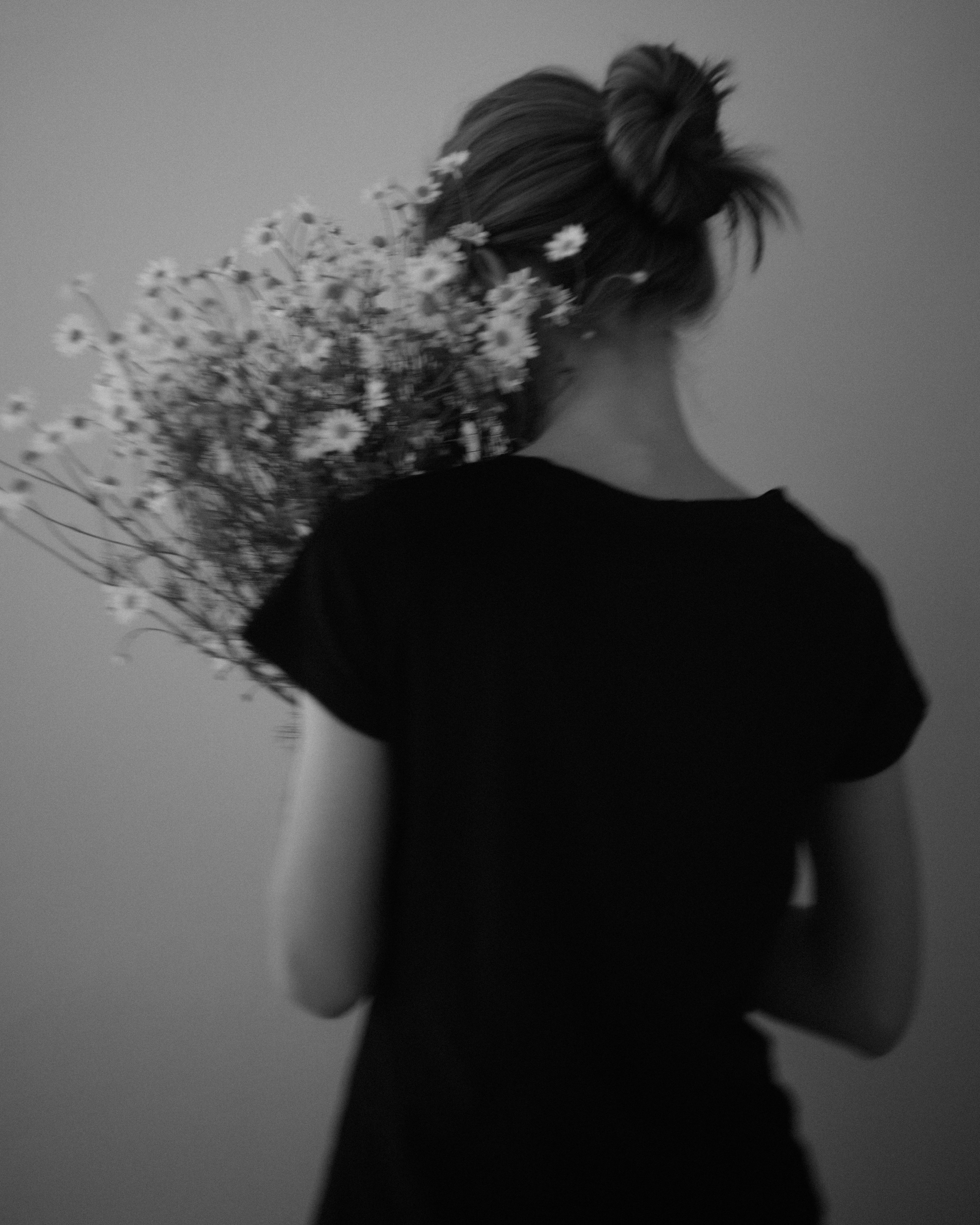A person in a black shirt holding a bouquet of daisies