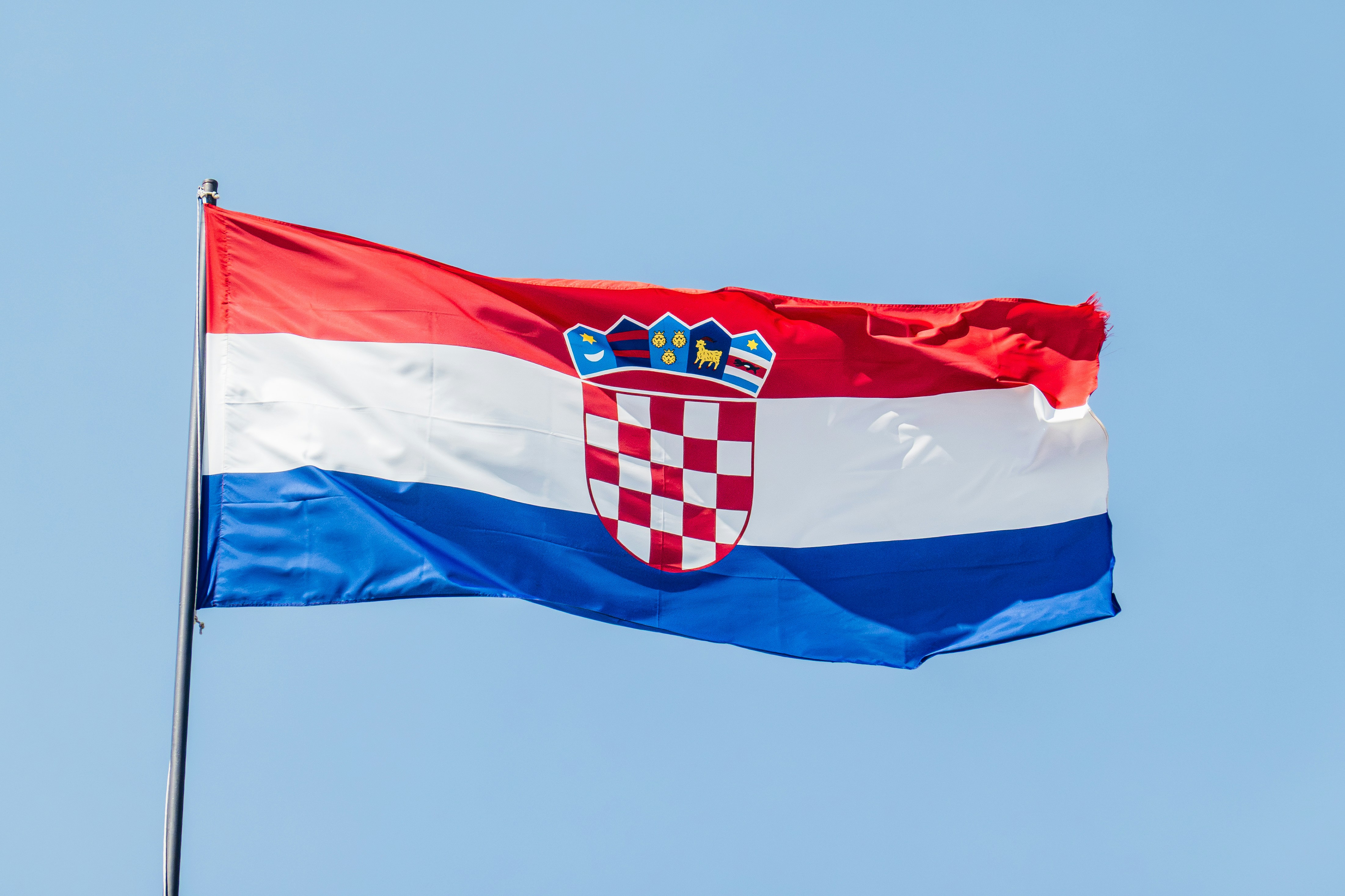 The flag of Croatia waving against a clear blue sky