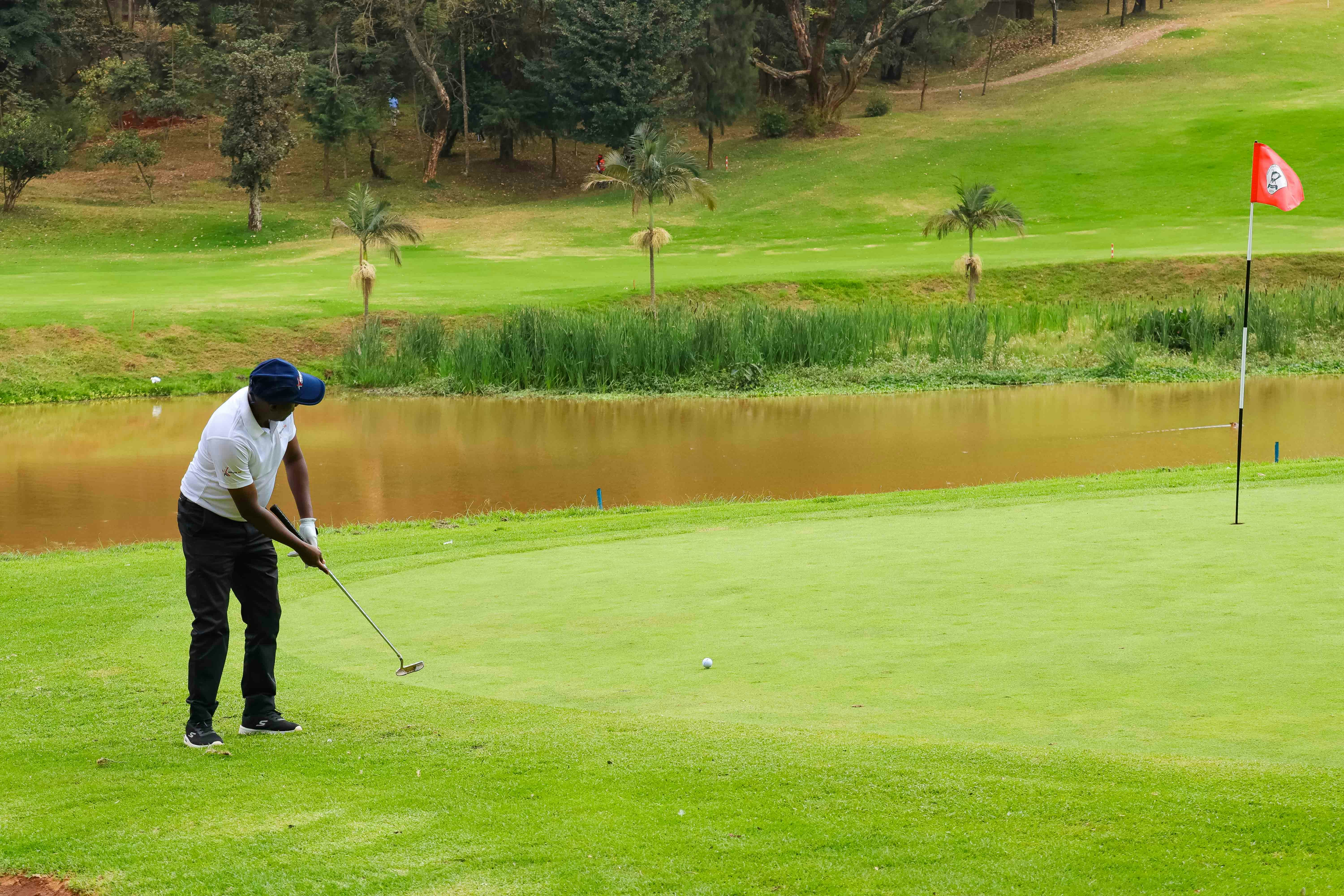 A golfer putting on a green beside a pond on a golf course