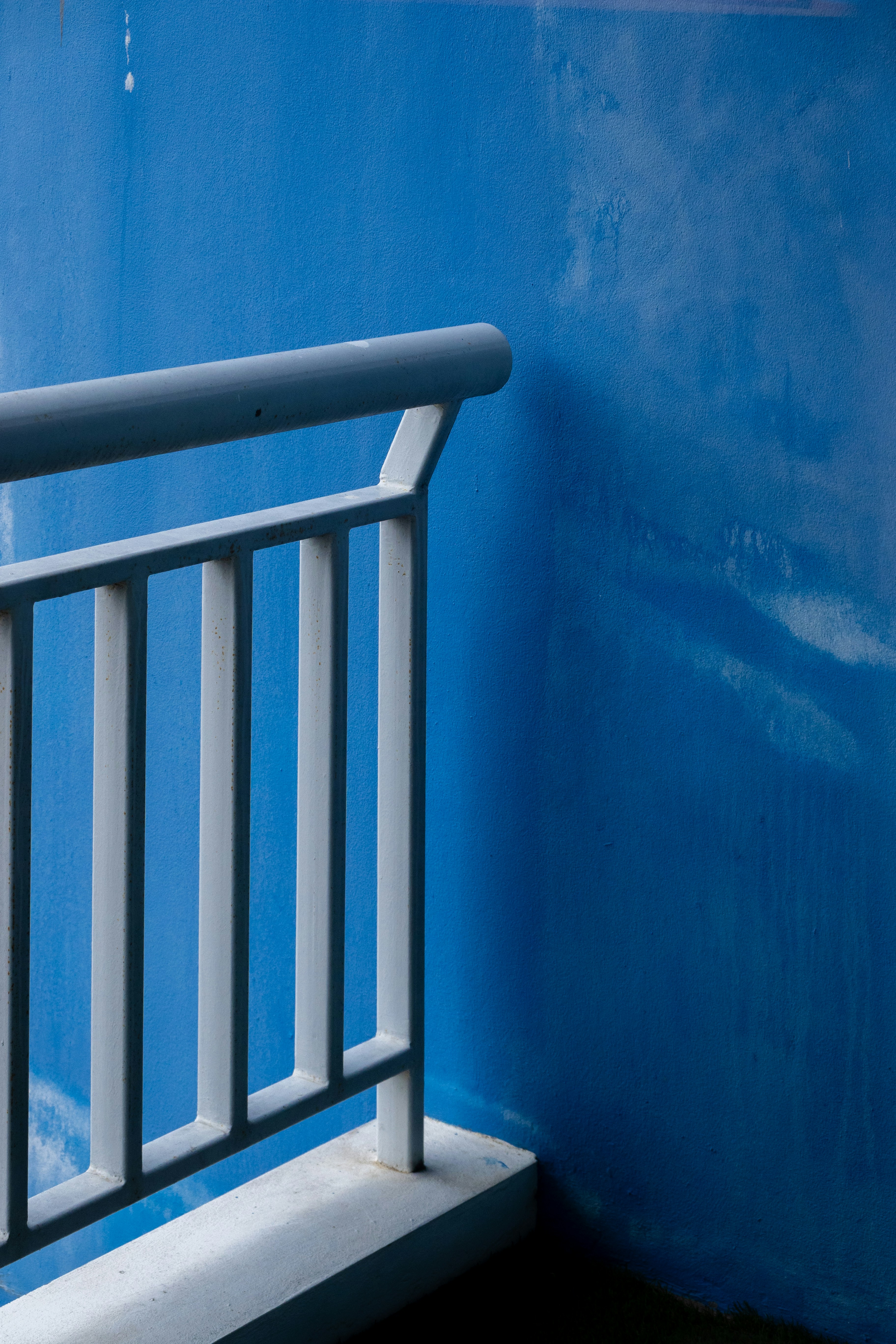 A white metal railing against a vibrant blue wall