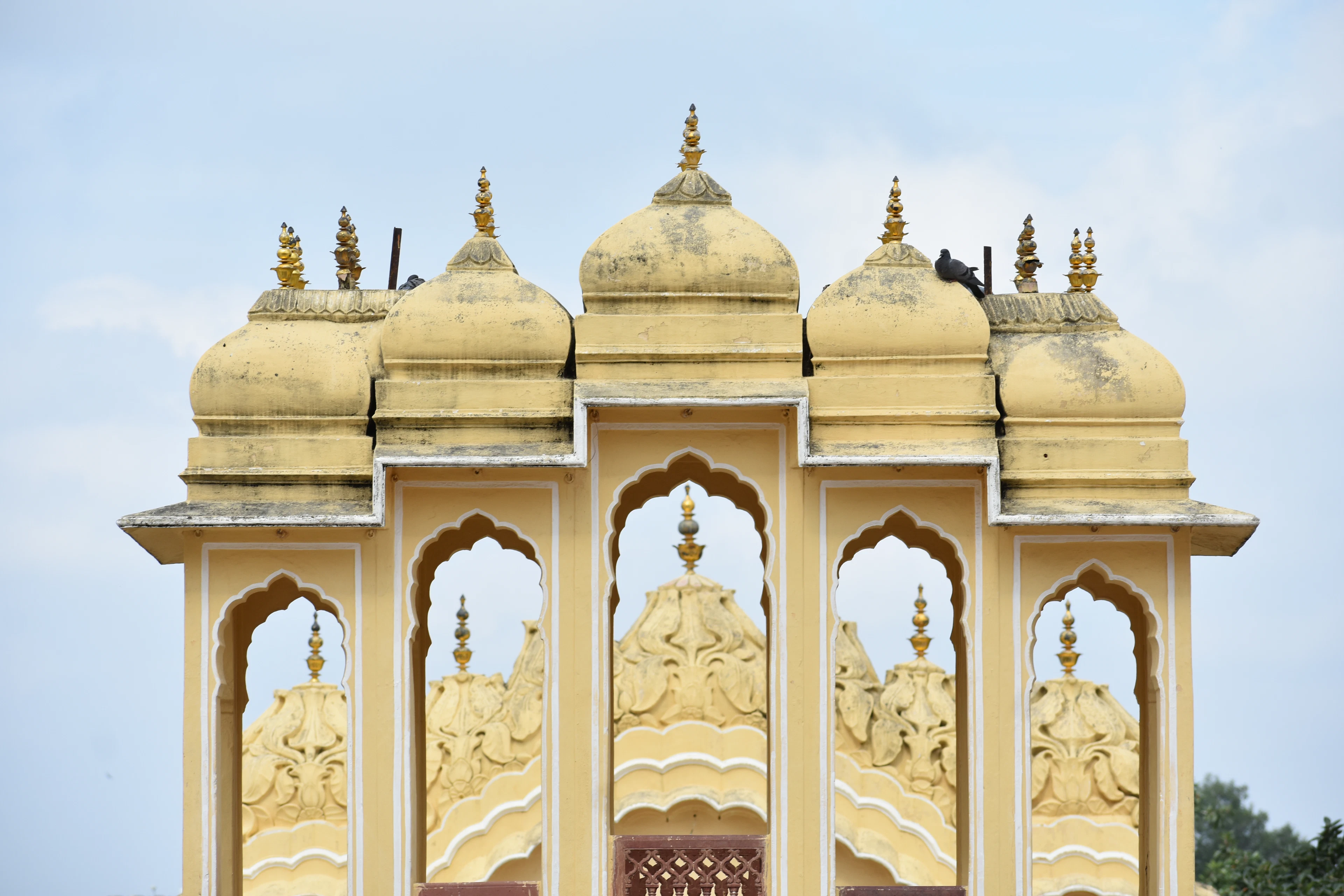 Domed chhatris with arched openings against a pale sky