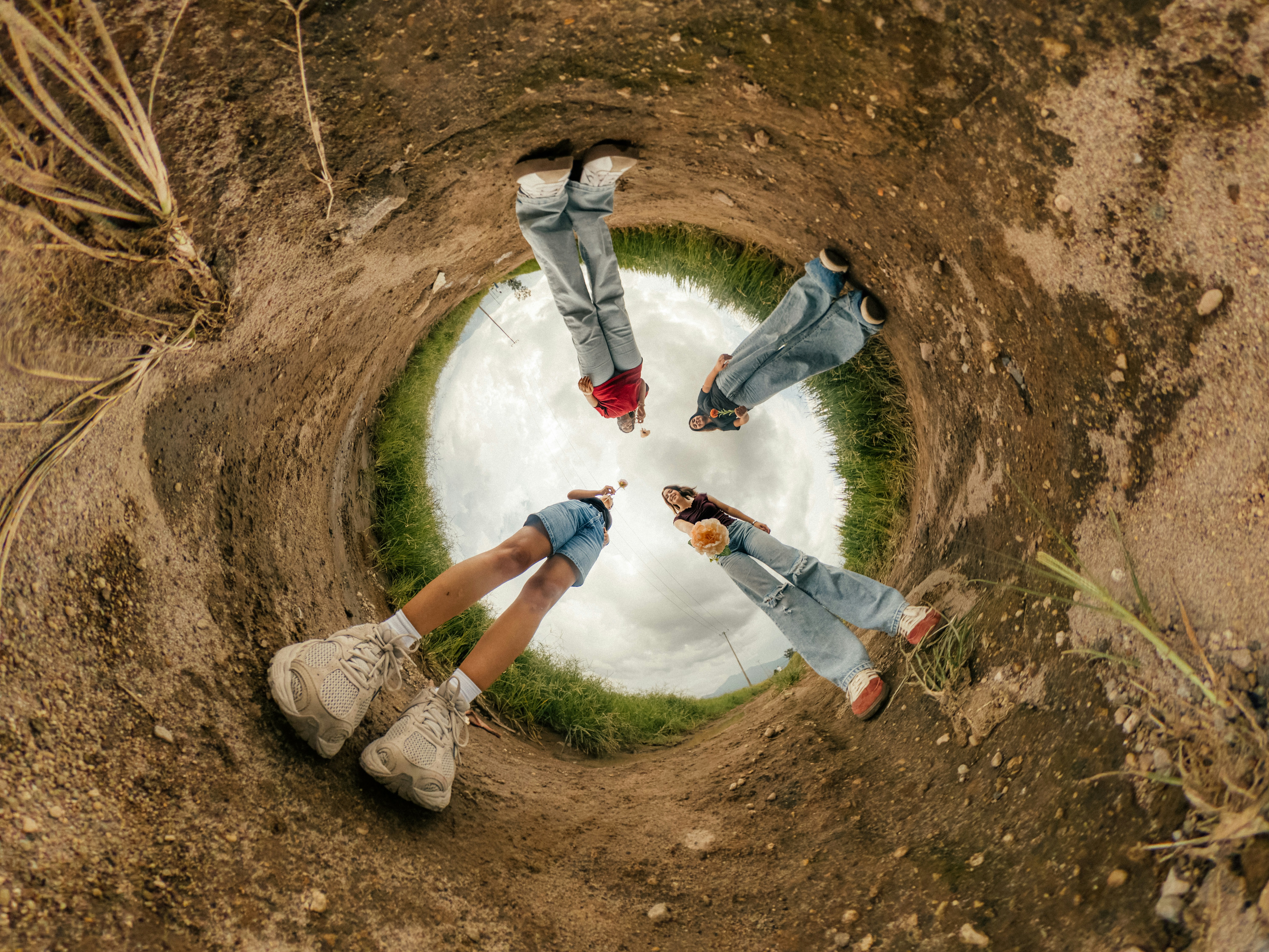 Four people standing in a circle on a dirt path under a cloudy sky