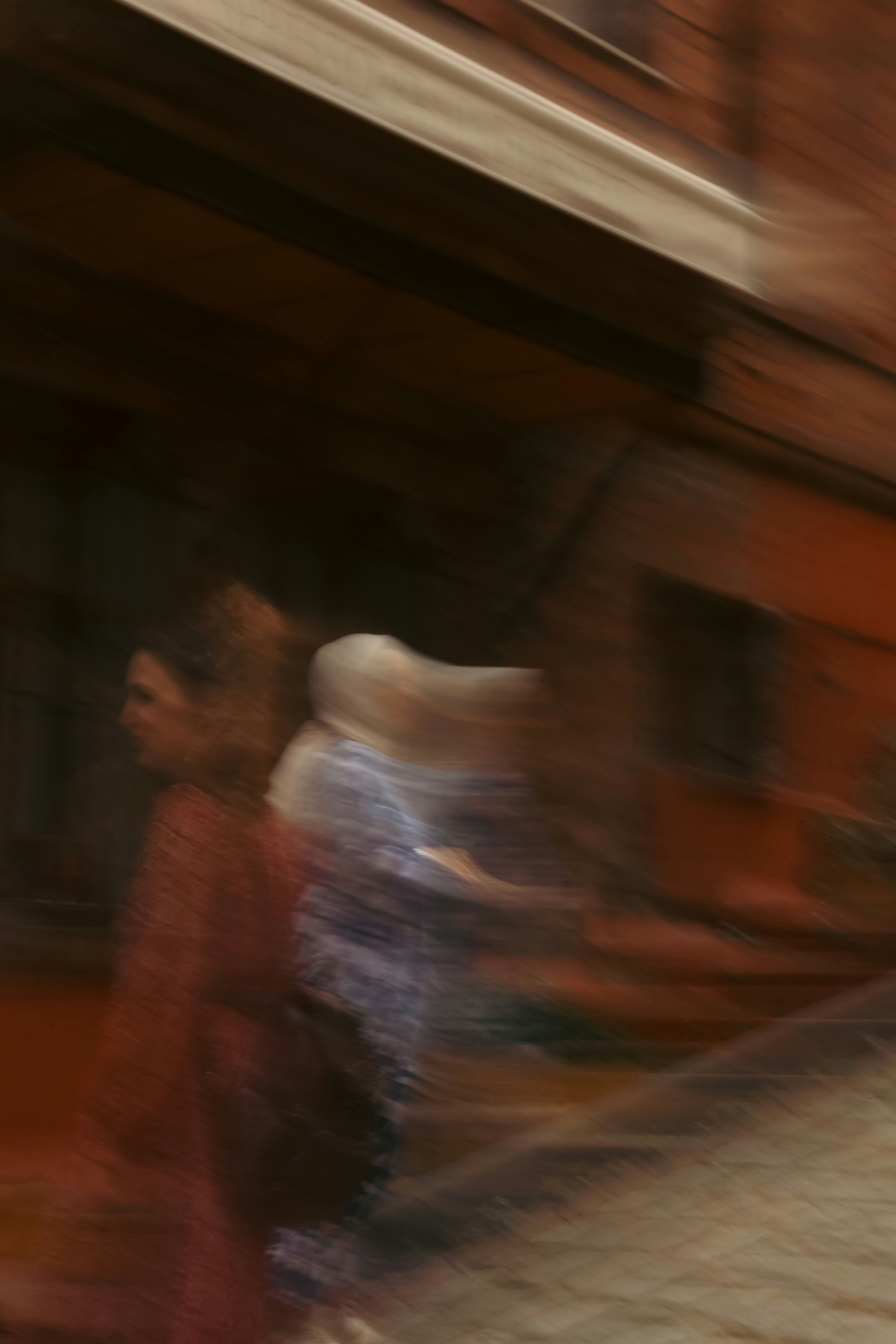 Two people walking past a rustic wooden building in a motion blur