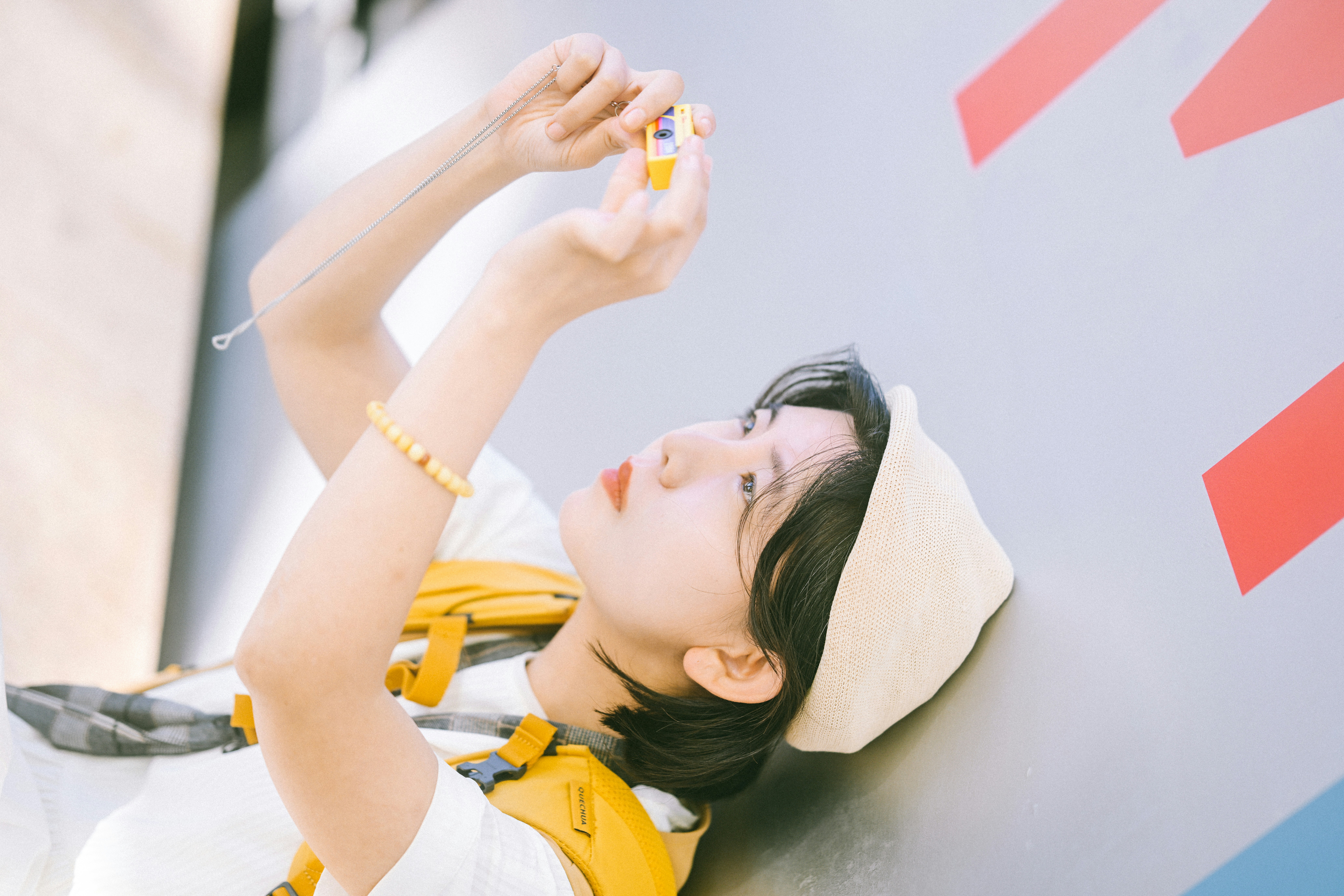 A person in a beige hat holding a small yellow camera above their head