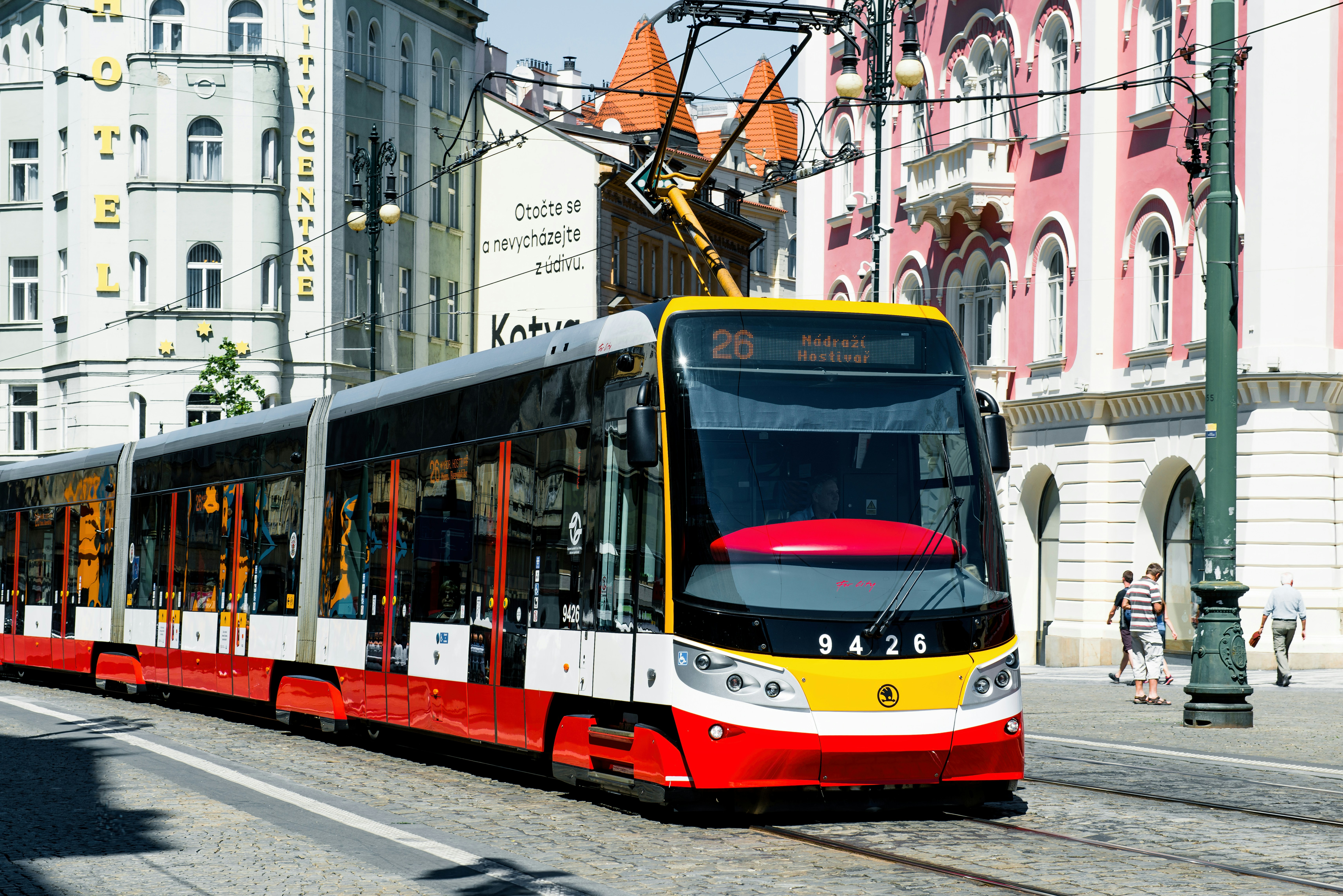 A red and yellow tram on cobblestone tracks in Prague city center
