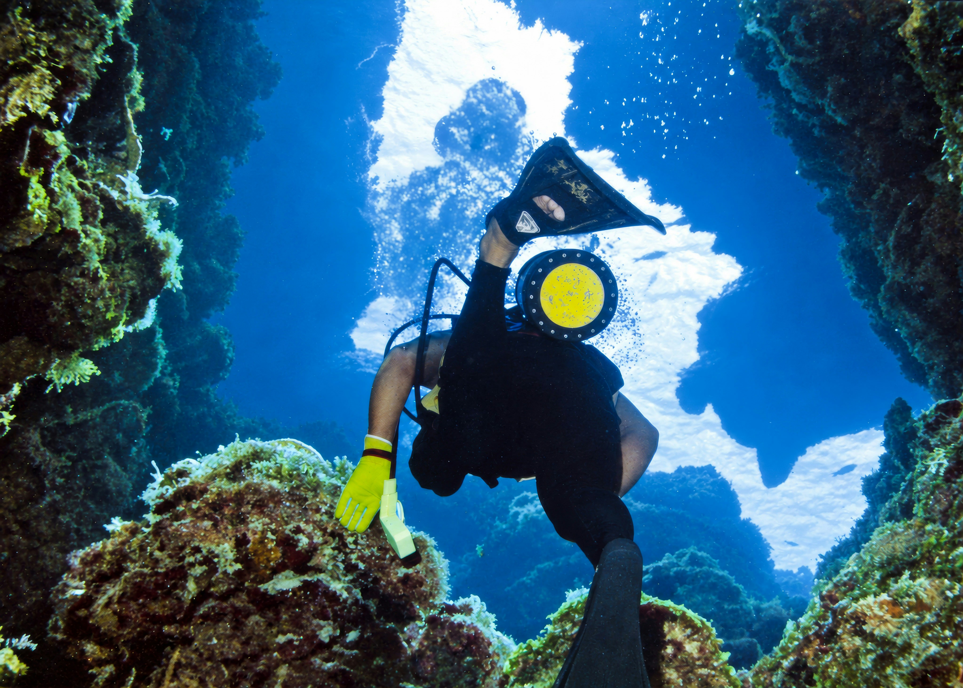 Scuba diver ascending through a reef swim-through in Cozumel