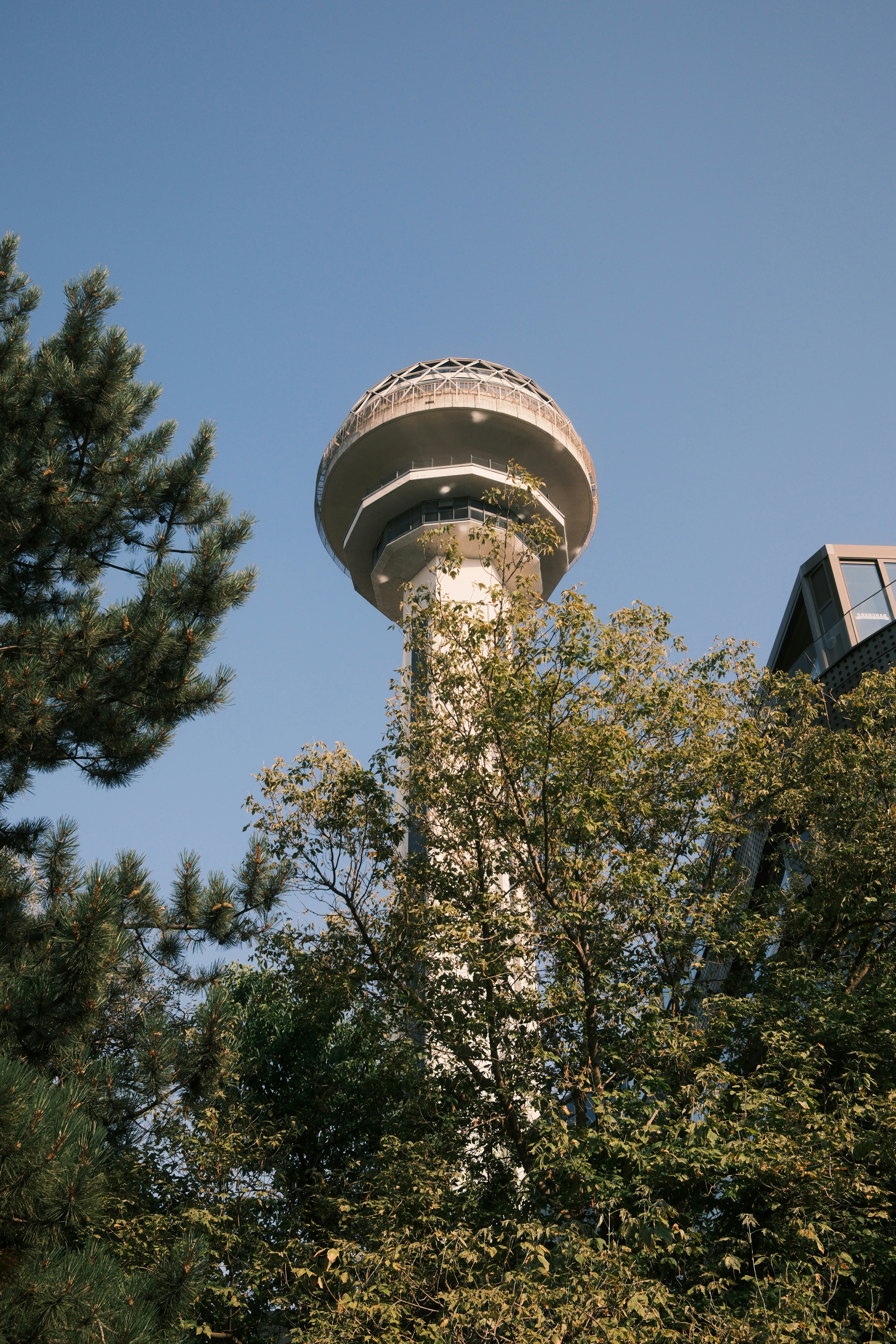 Der Atakule-Turm, der sich über grüne Bäume vor einem klaren blauen Himmel in Ankara erhebt