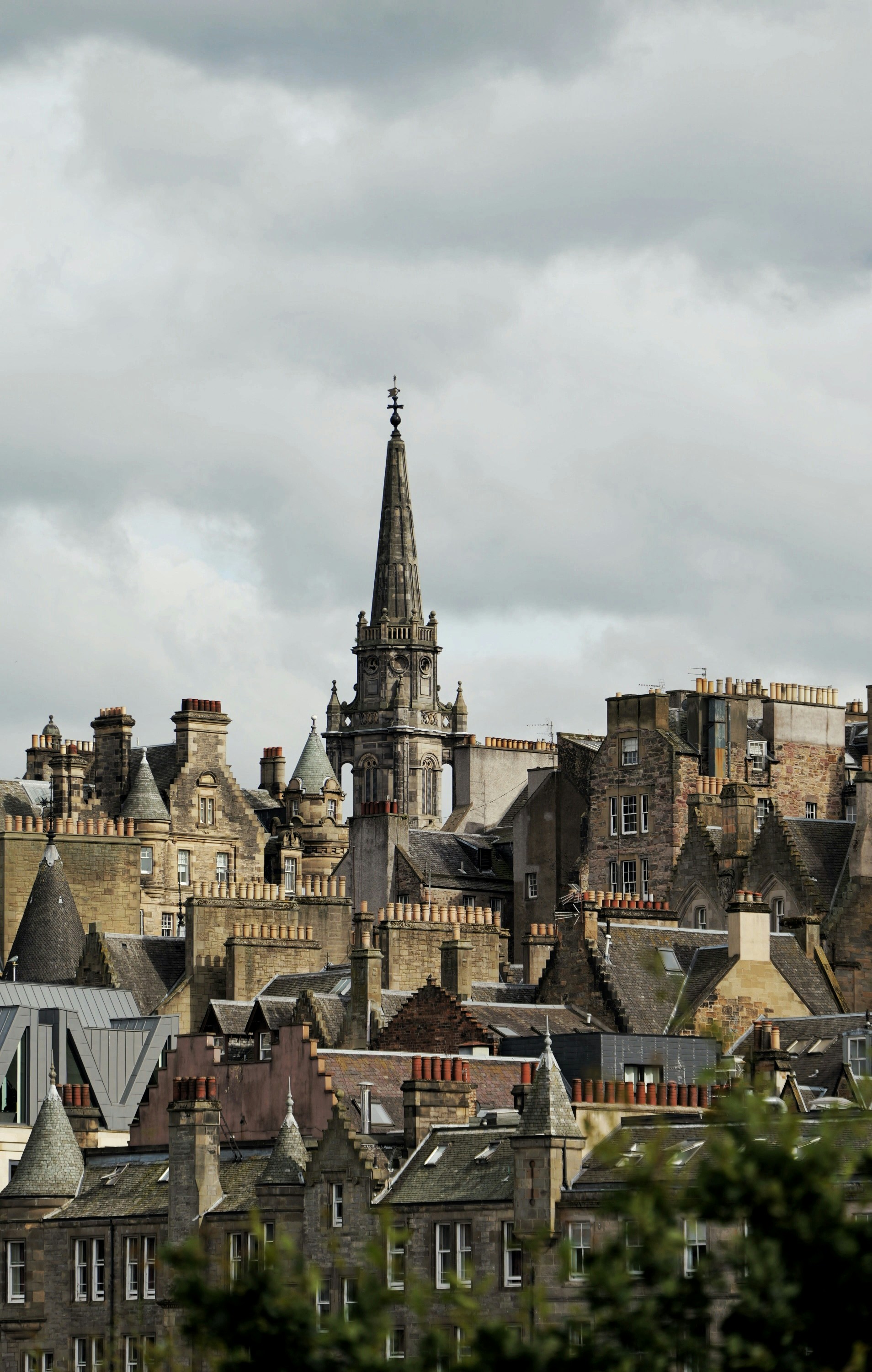 Stone church spire rising above a dense cityscape of historic buildings in Edinburgh