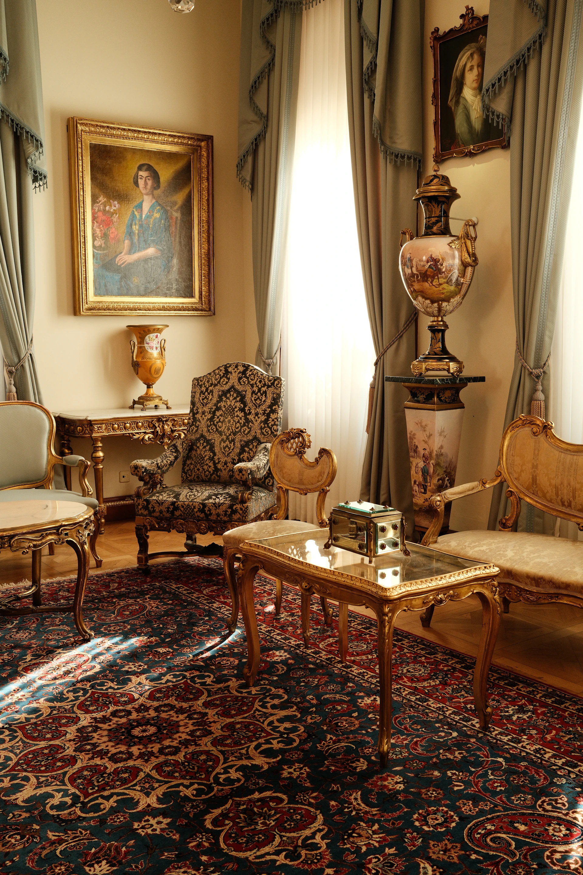 An ornate living room with antique furniture, oil paintings, and a patterned rug