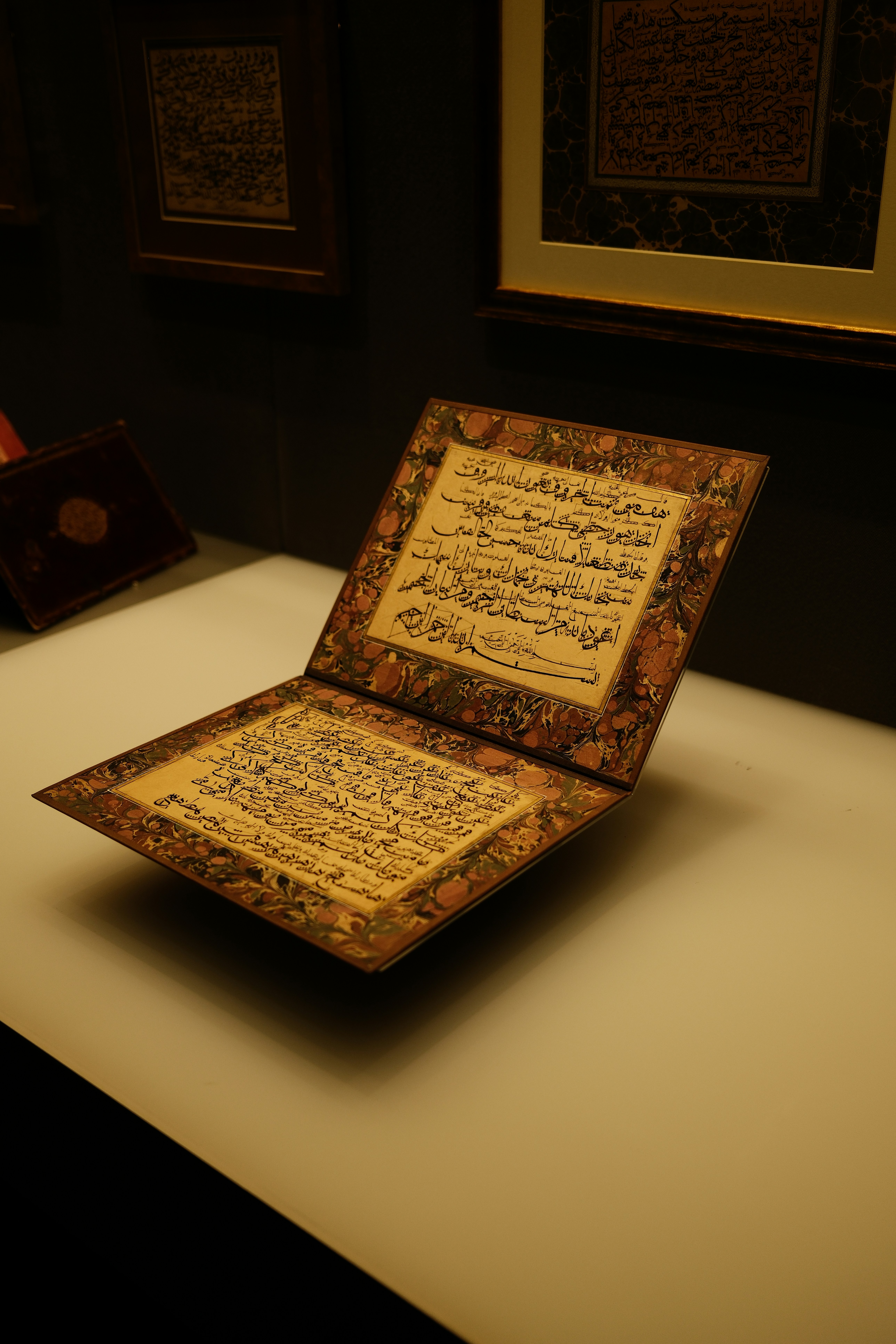 Ein offenes Manuskript mit kunstvollen floralen Rändern und schwarzer arabischer Kalligraphie ist ausgestellt