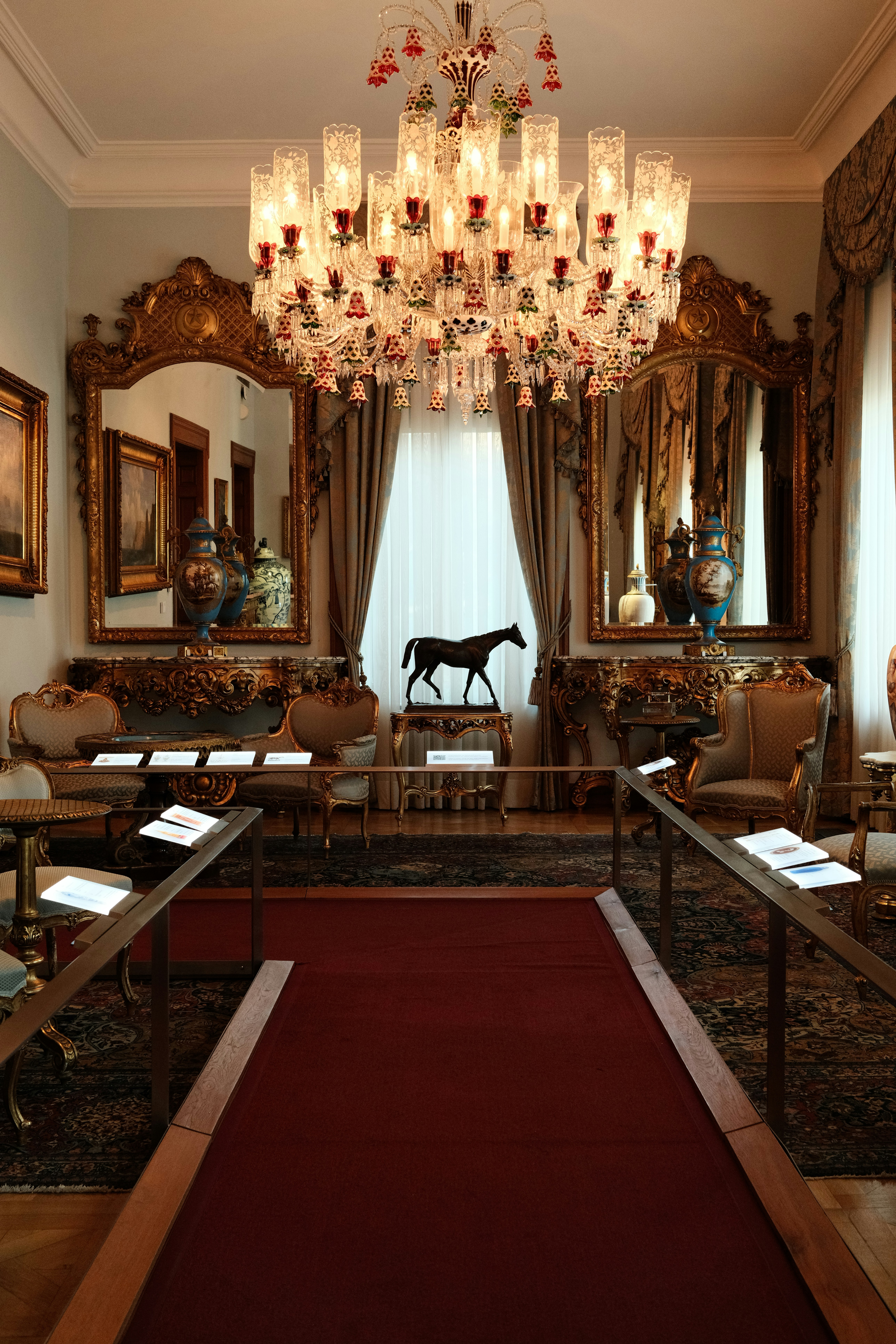 Ein prächtiger Raum mit einem Kristallkronleuchter, kunstvollen Spiegeln und einer Pferdeskulptur
