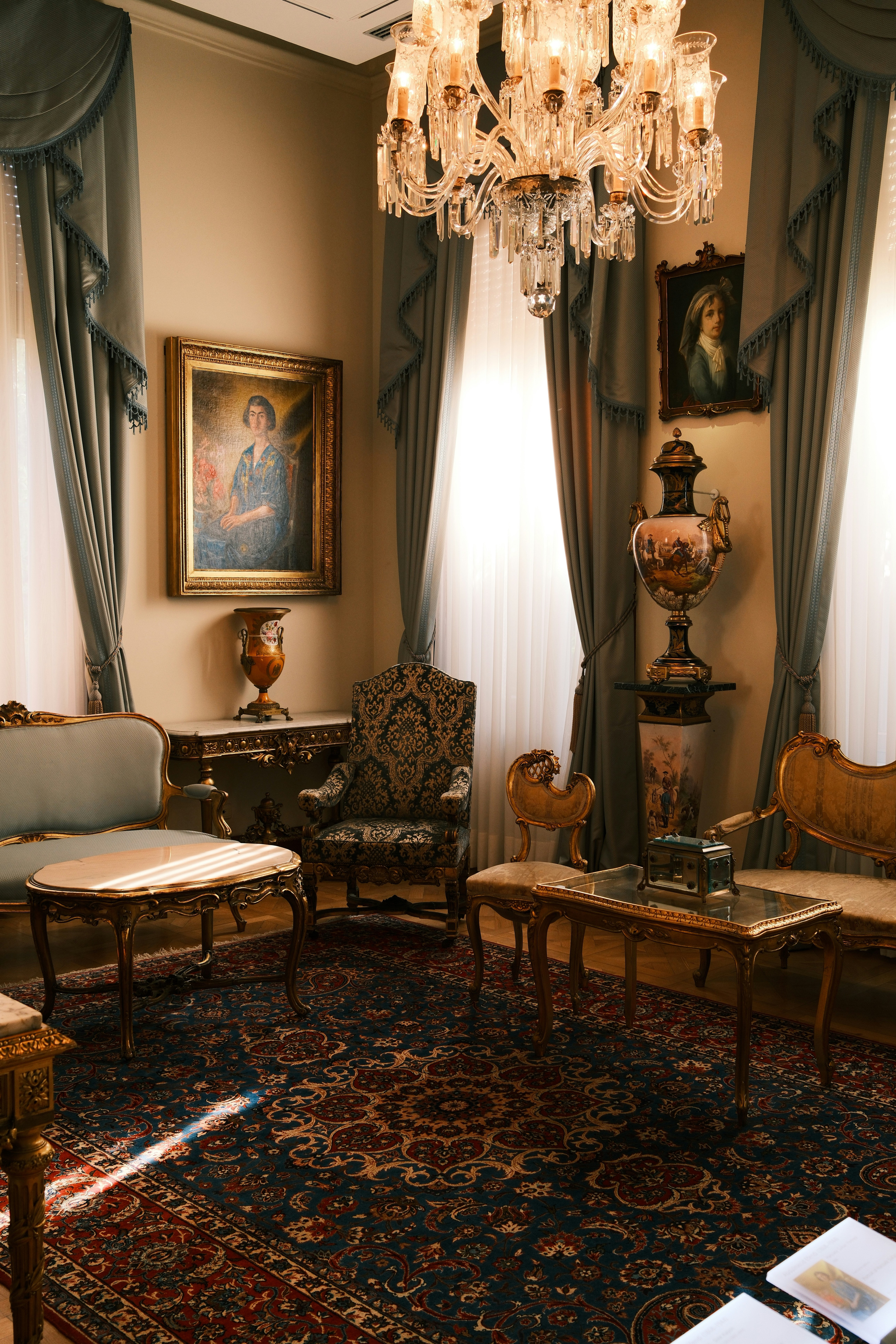 Ein formelles Wohnzimmer mit kunstvollen Möbeln, einem Kristallkronleuchter und Ölgemälden