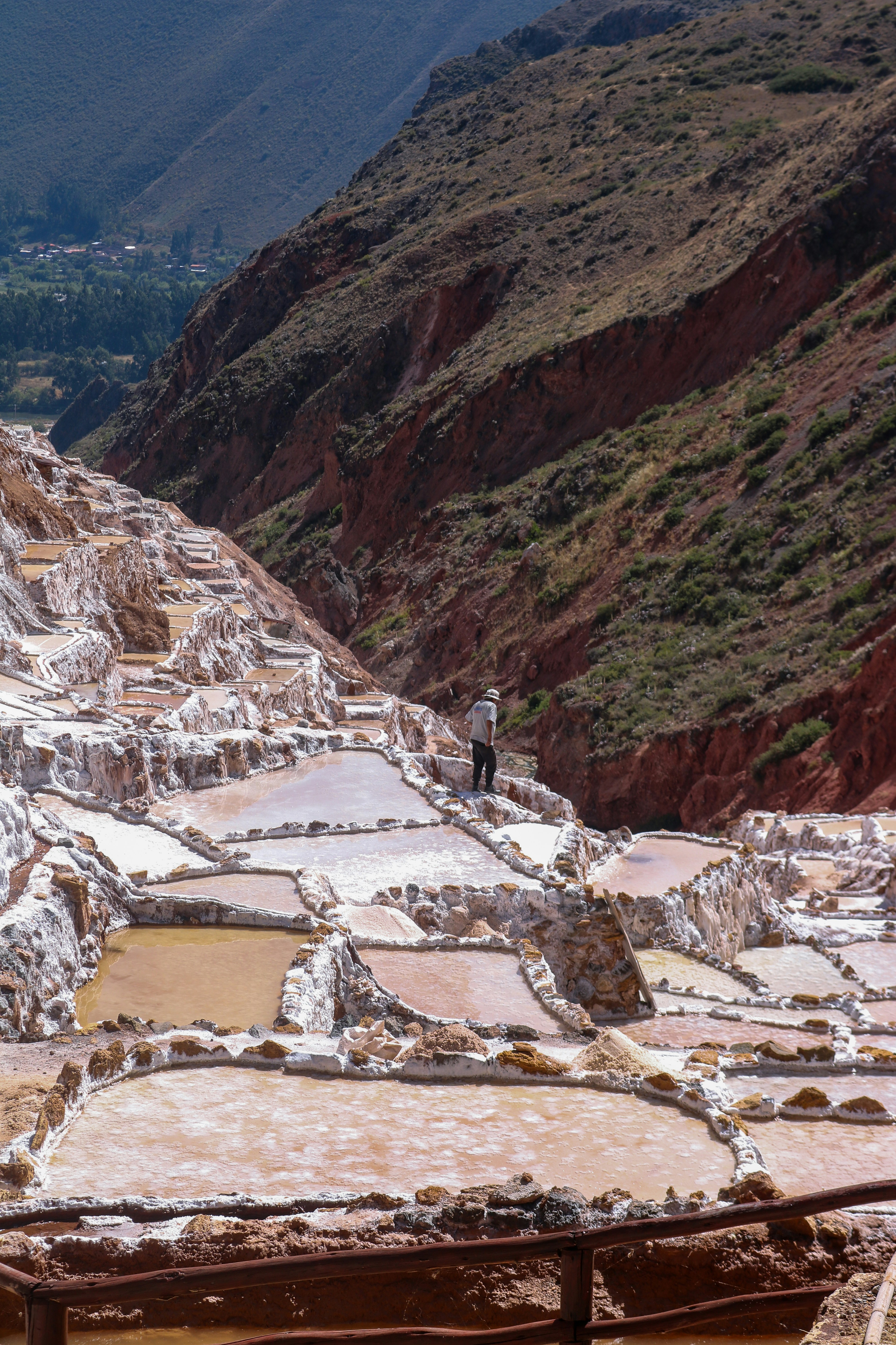 A person walking among terraced salt evaporation ponds in the Maras valley