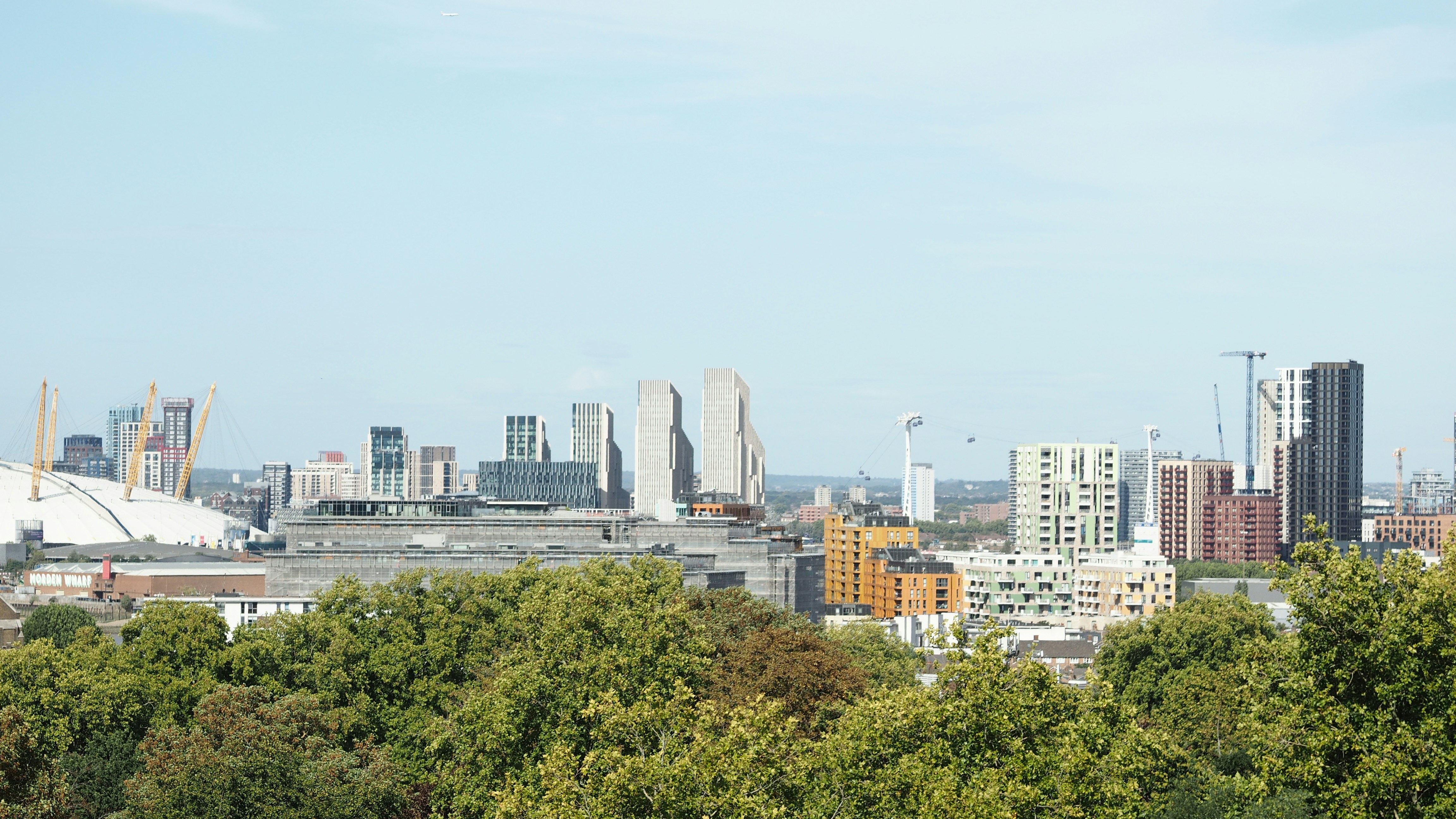 Lo skyline di Londra con l'O2 Arena e i moderni palazzi di appartamenti sopra alberi verdi